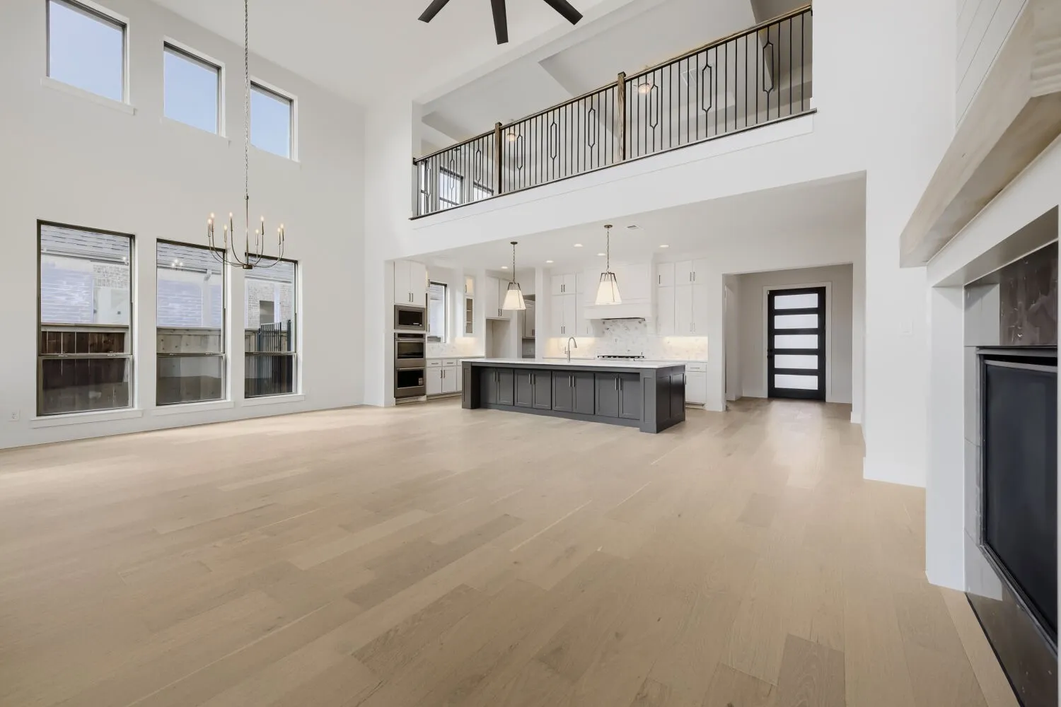 Expansive open-concept space featuring high ceilings, wood-finish flooring, and a contemporary kitchen with a dark-toned island