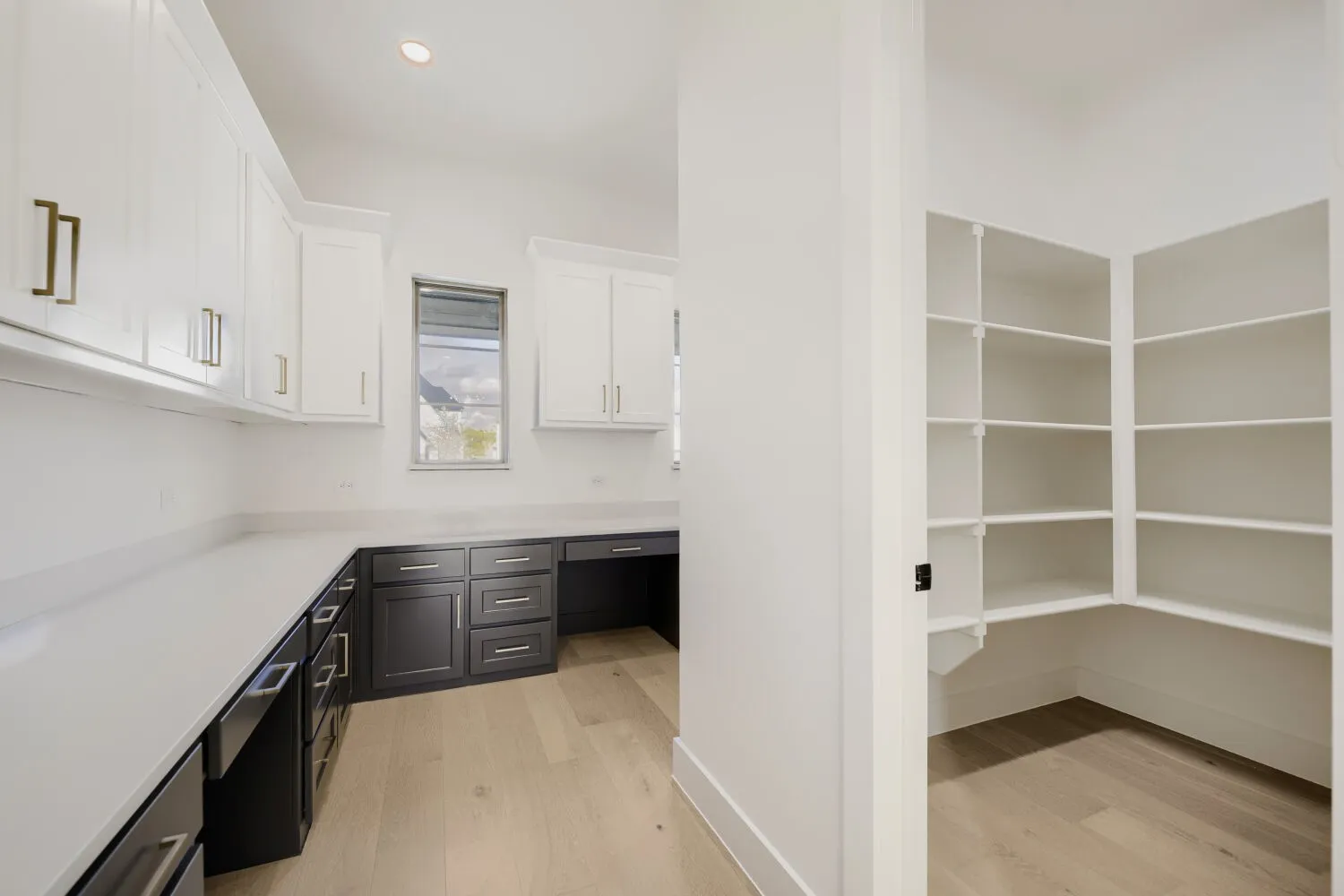 Workstation with extensive countertop space, upper and lower cabinetry, and wood-finish flooring