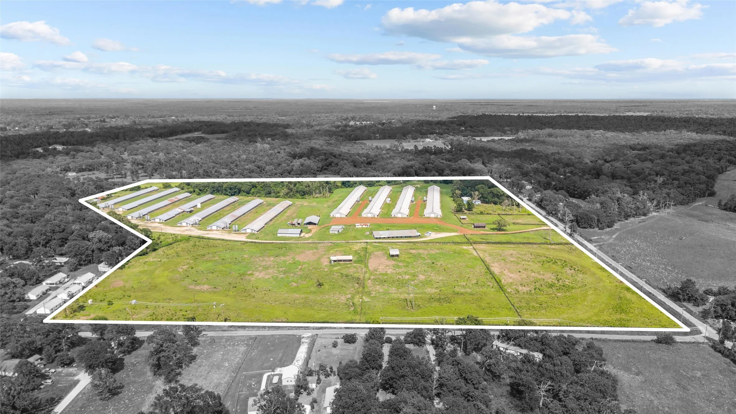 Expansive agricultural property featuring multiple poultry houses, extensive open land, and perimeter fencing