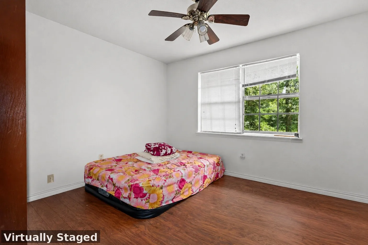 Interior space featuring wood-finish flooring, white walls, and a window with blinds