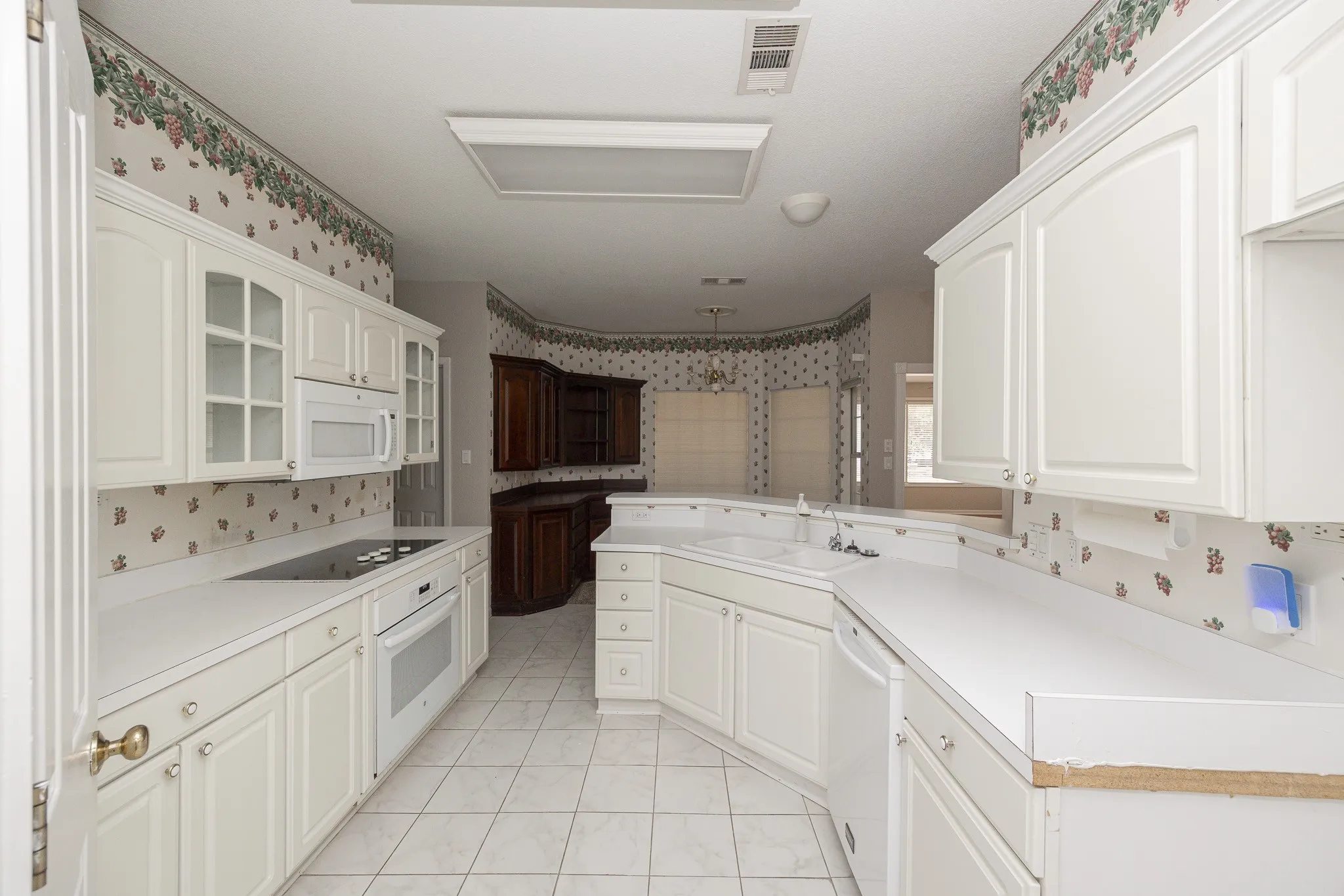 Kitchen featuring white cabinetry, white countertops, built-in microwave, and a cooktop with an oven