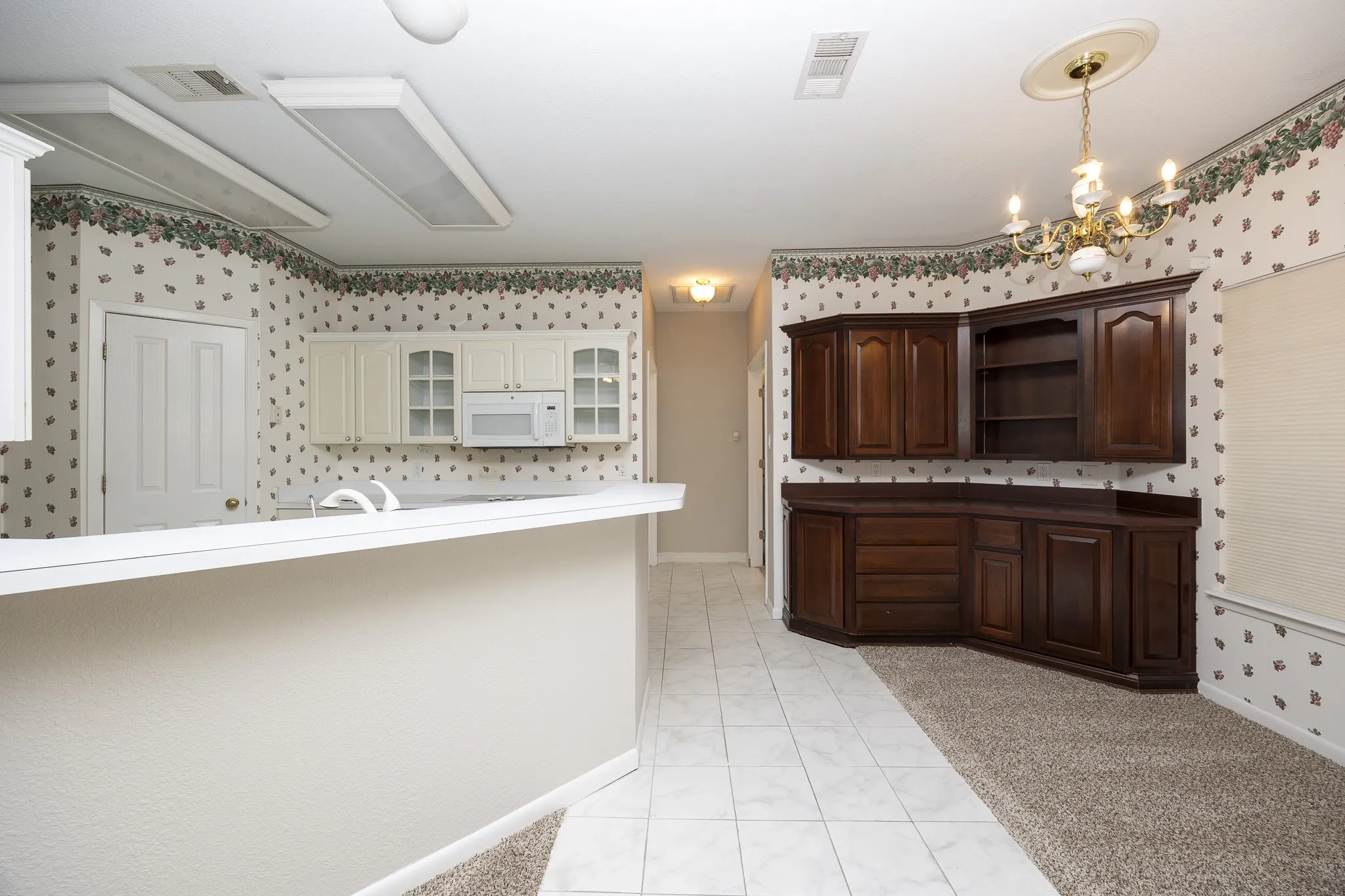 Kitchen area featuring a breakfast bar, white cabinetry, a built-in microwave, and tile flooring