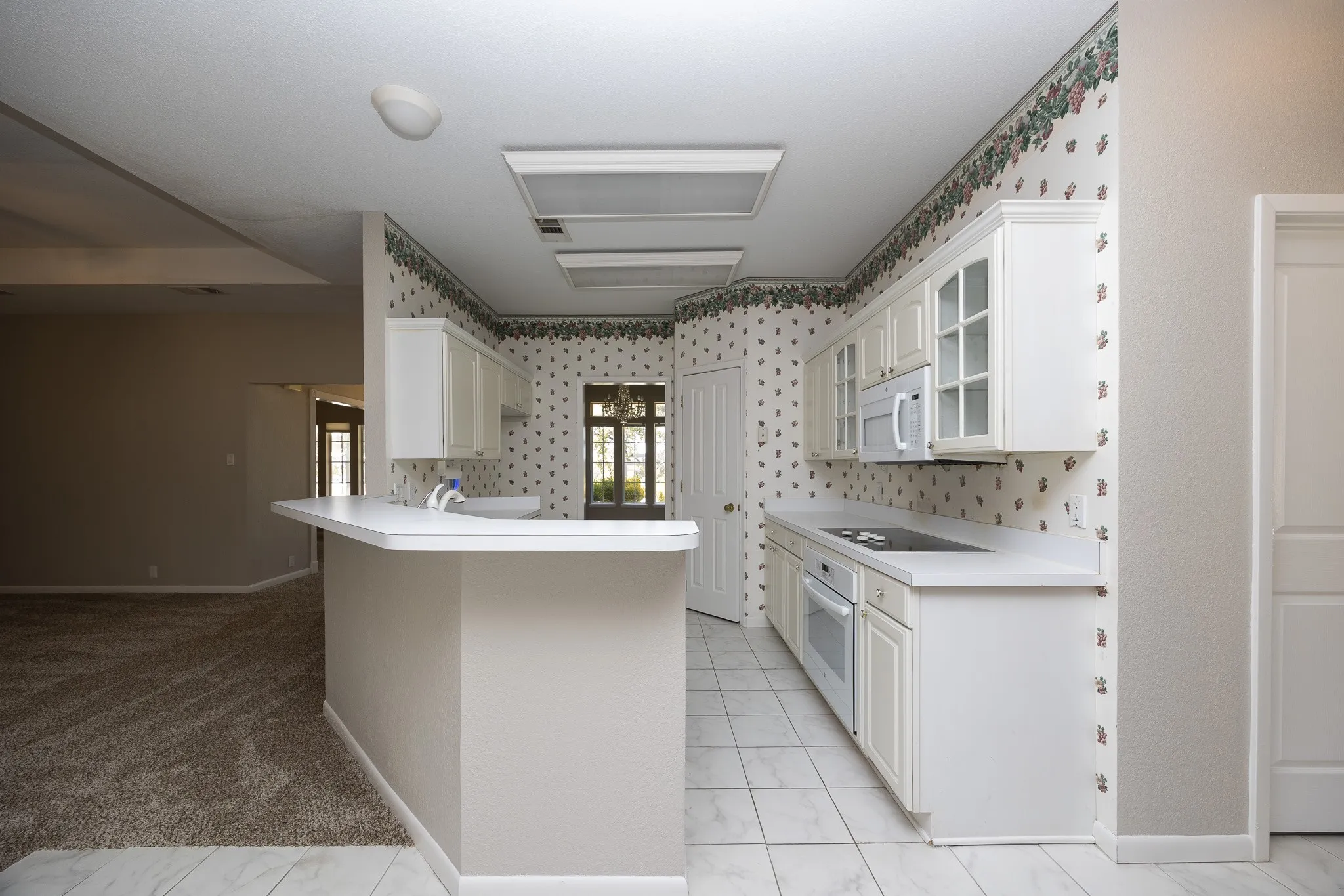 Kitchen featuring white cabinetry, a built-in microwave, a flat-top electric range, and a breakfast bar