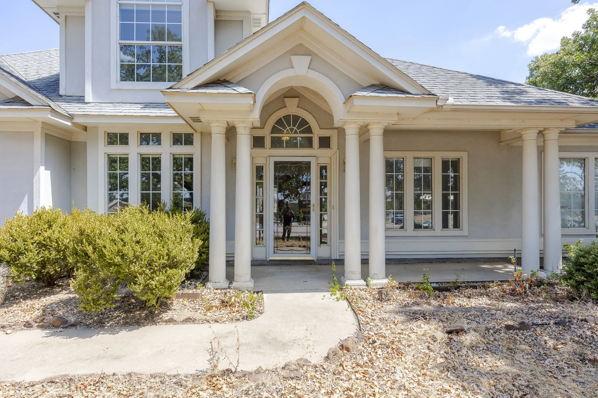 Entryway featuring a portico with four columns and an arched transom window