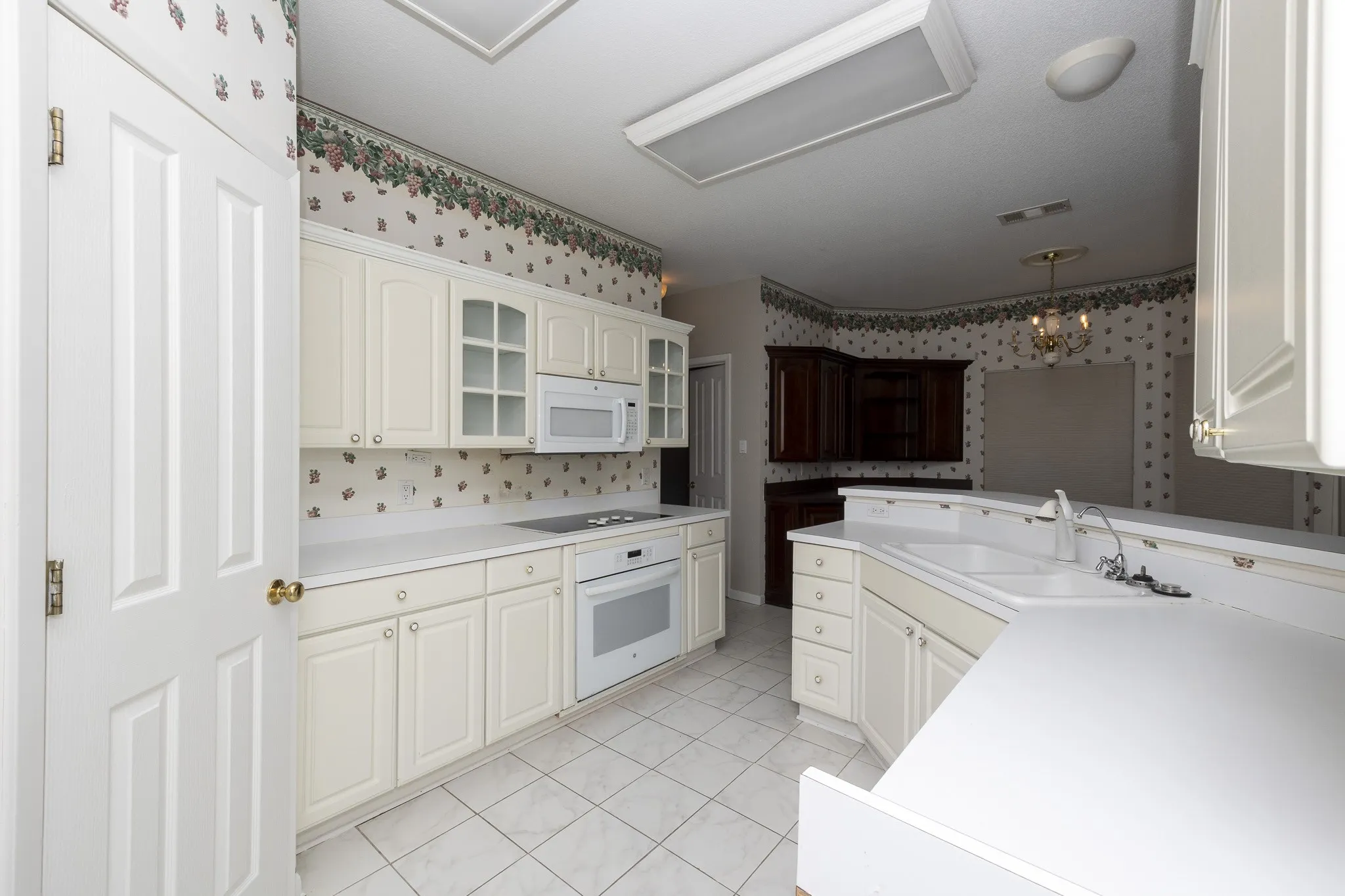 Kitchen featuring white cabinetry, built-in white appliances, white countertops, and tile flooring