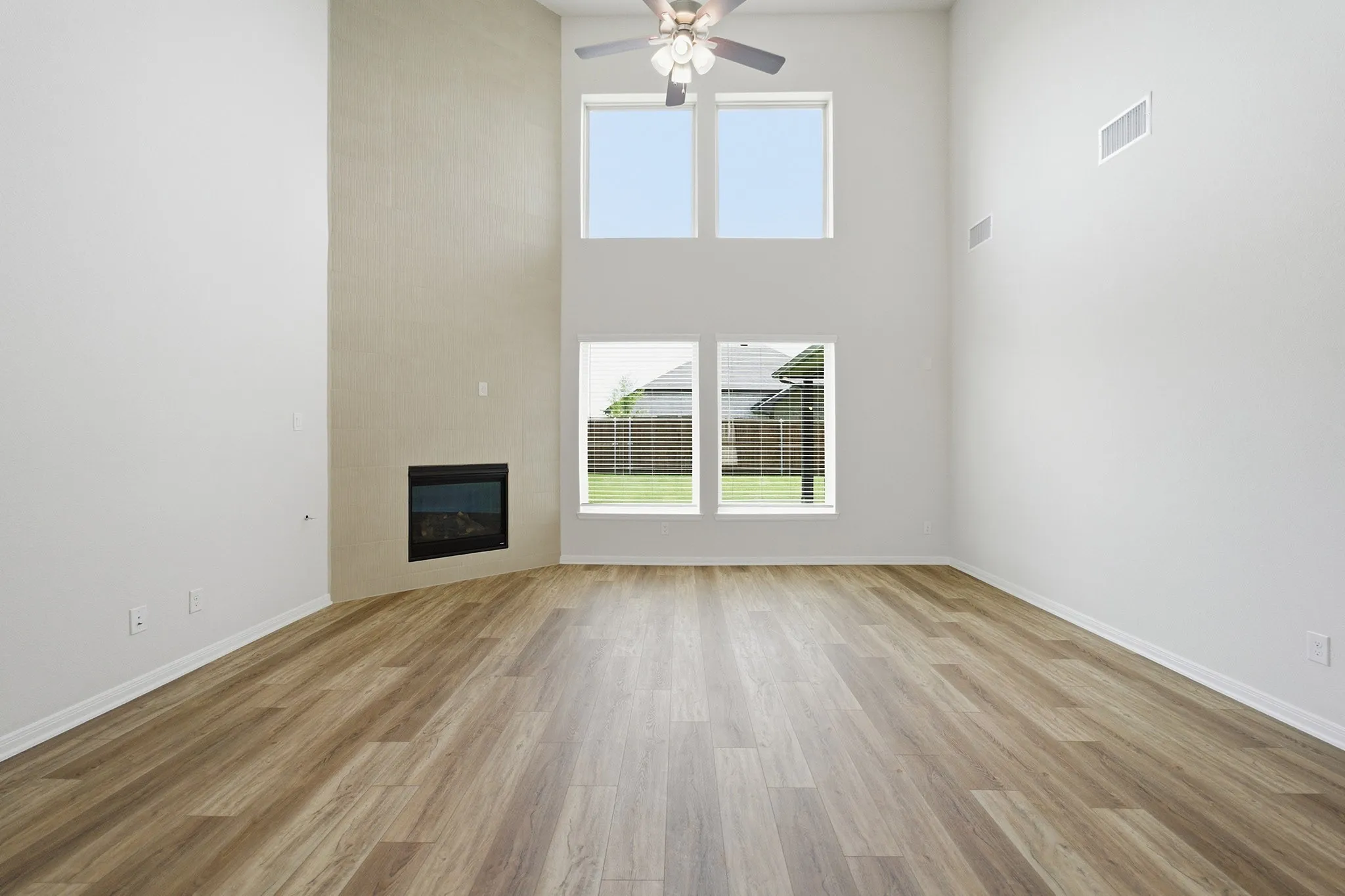 Spacious living area featuring high ceilings, wood-finish flooring, and a corner-set fireplace