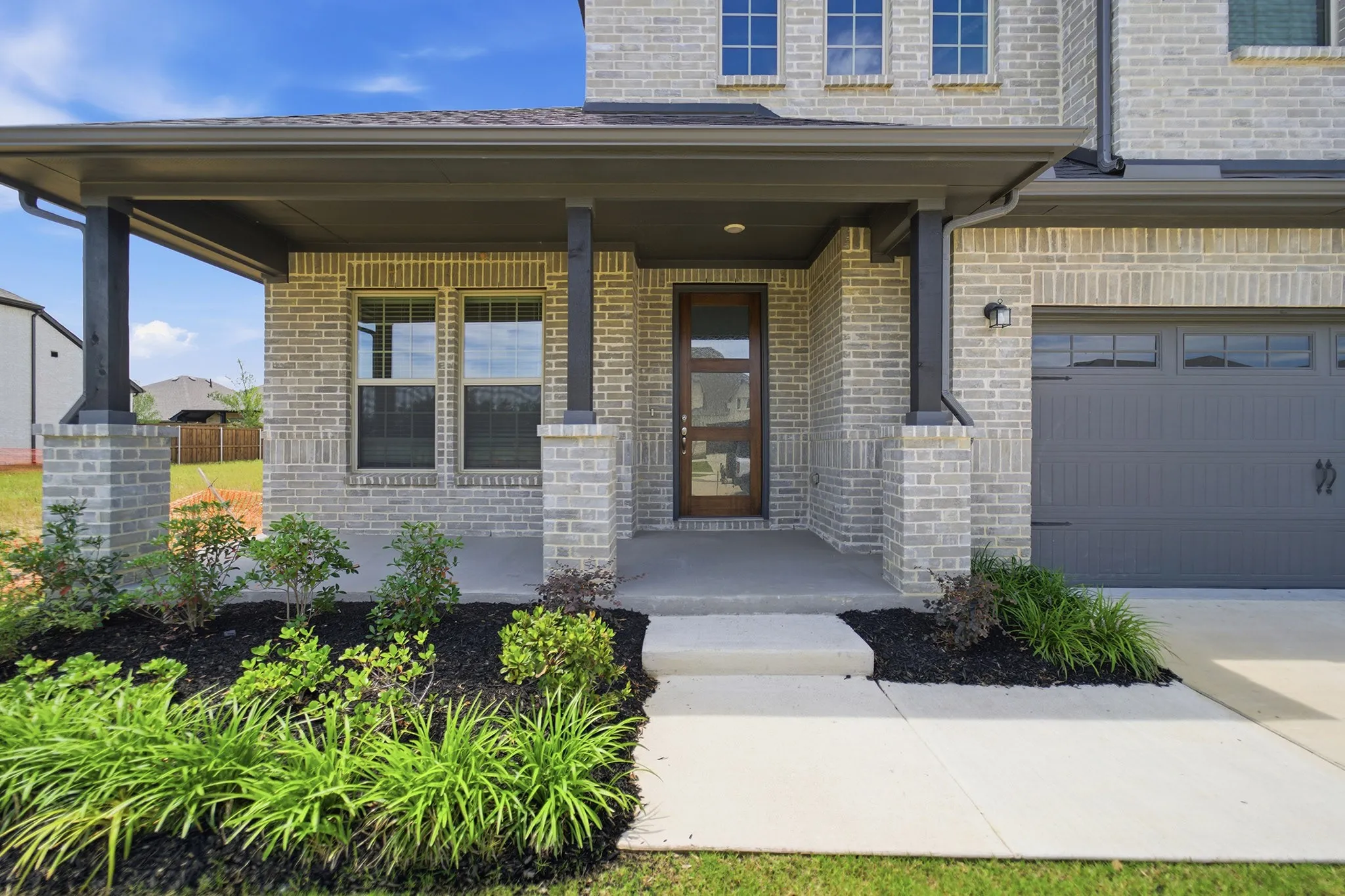 Light-colored brick exterior with dark trim and a covered front porch