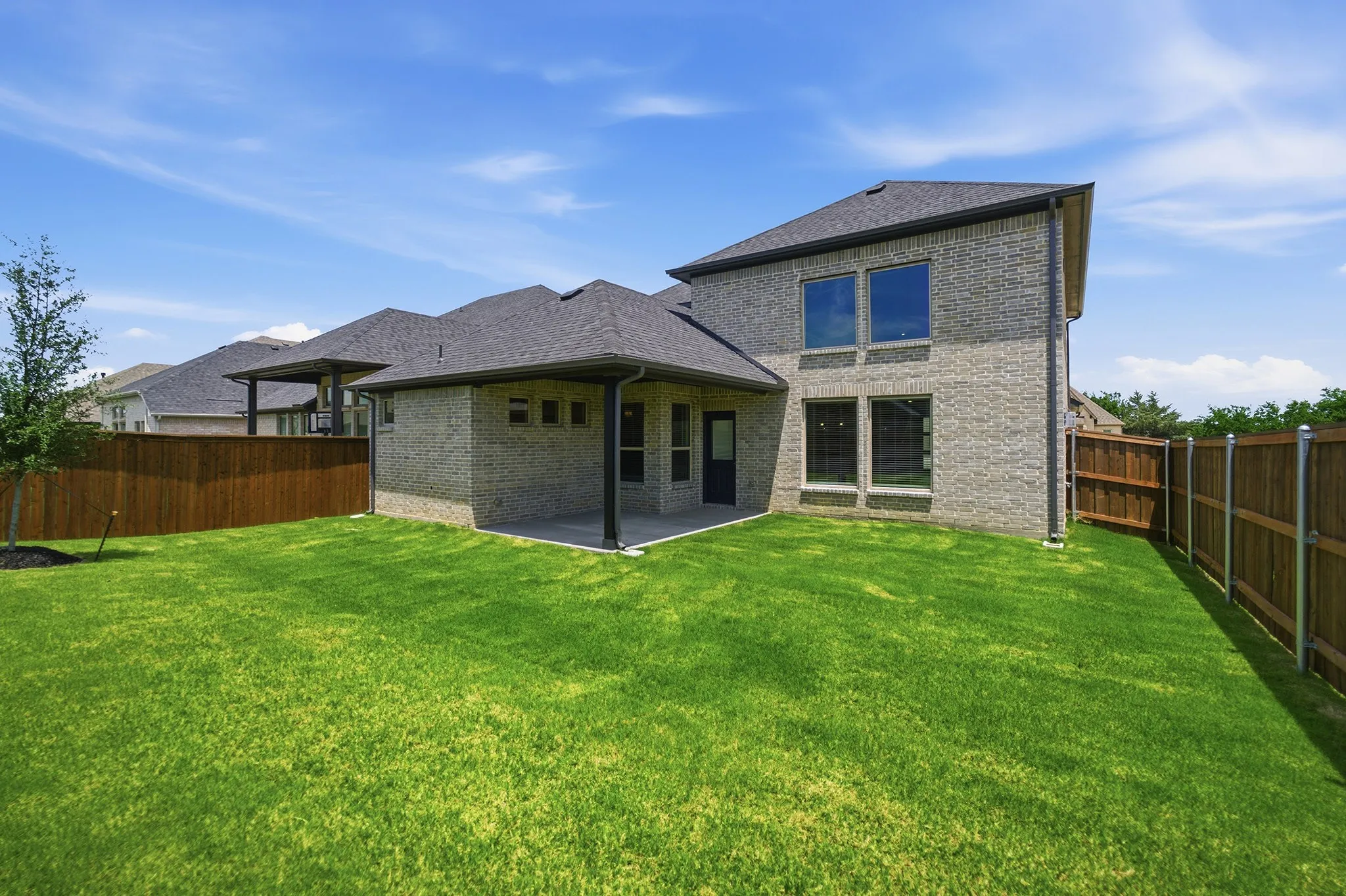 Expansive green lawn with a newly constructed brick exterior