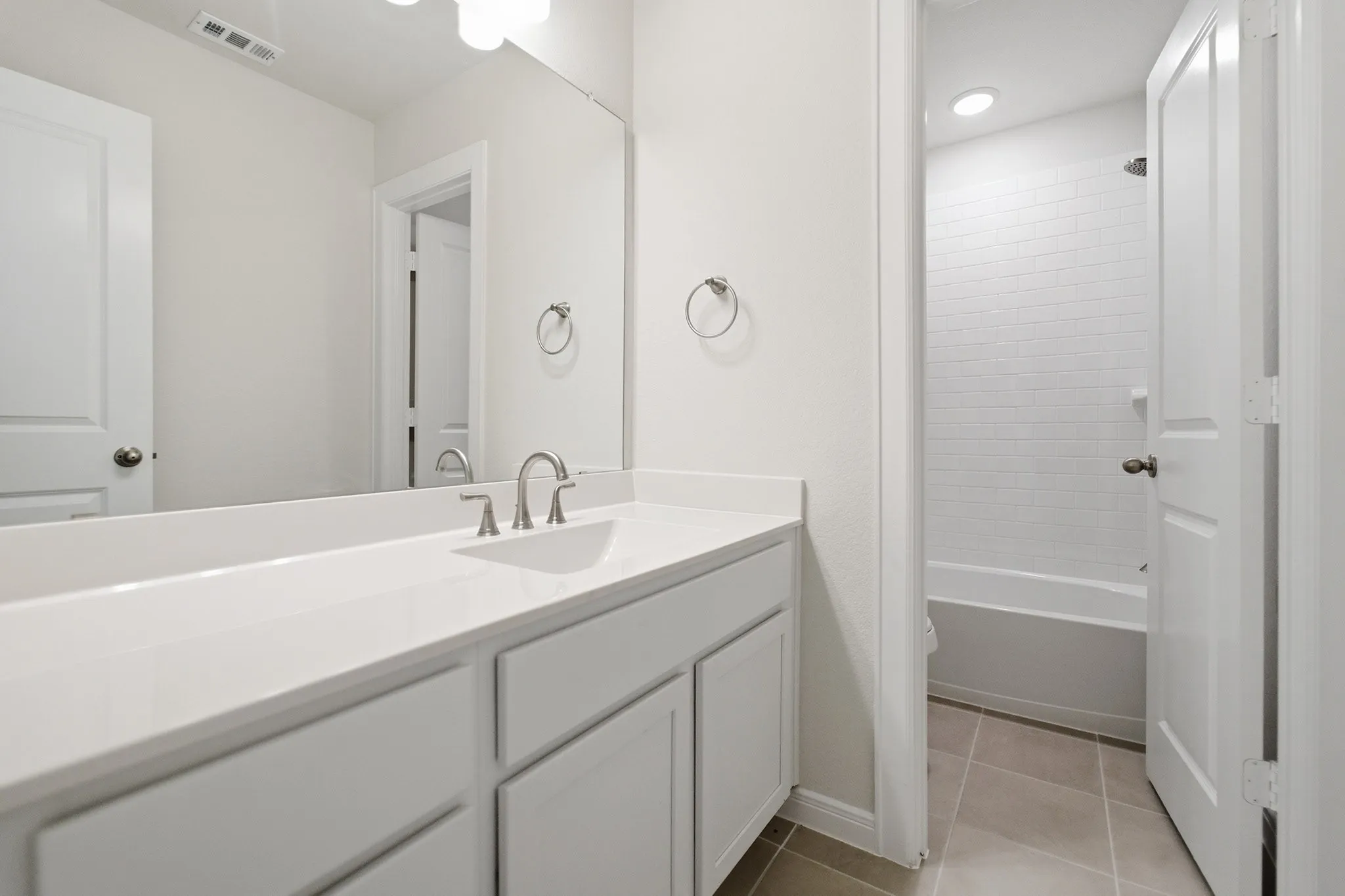 Modern bathroom vanity with a single basin sink, brushed nickel faucet, and a large wall-mounted mirror