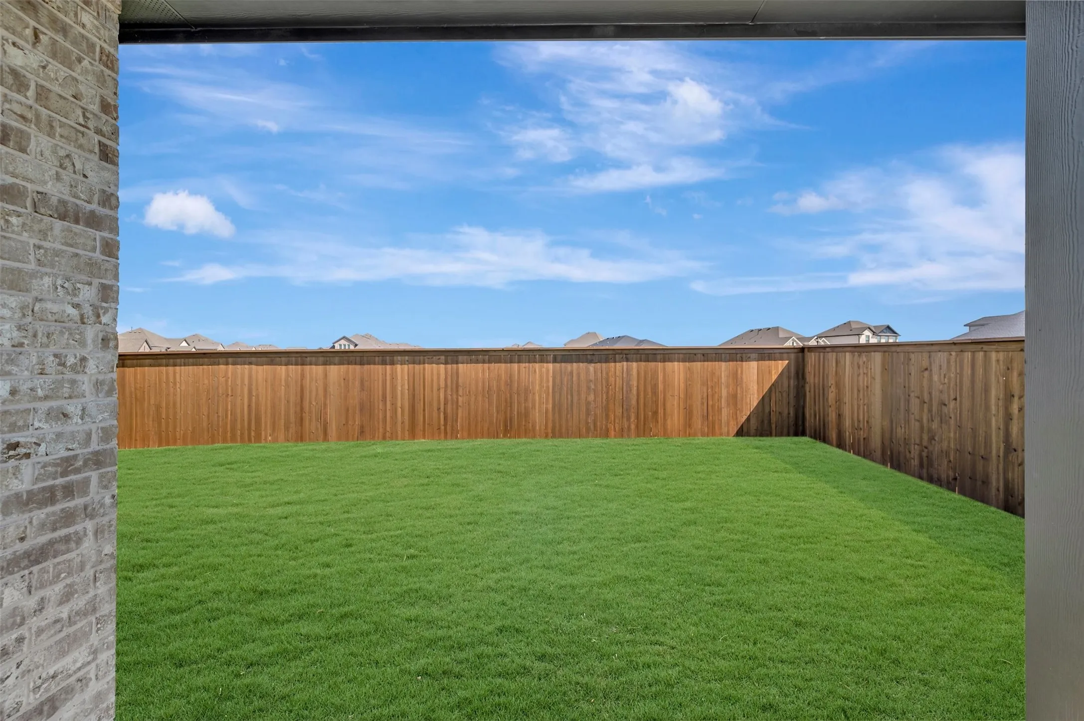 Expansive backyard featuring a lush lawn and perimeter wood fencing