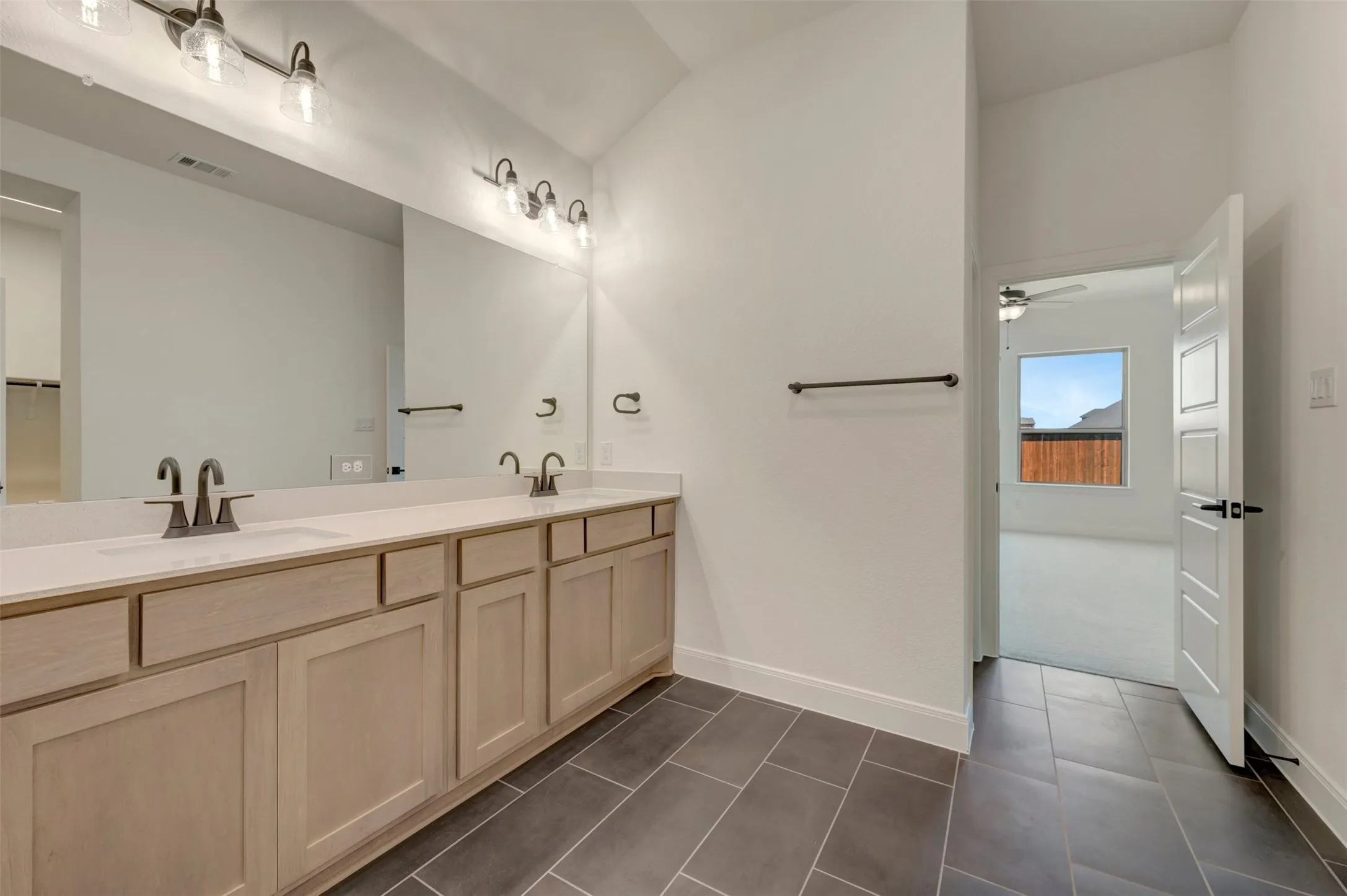 Dual vanity with light wood-finish cabinetry and undermount sinks