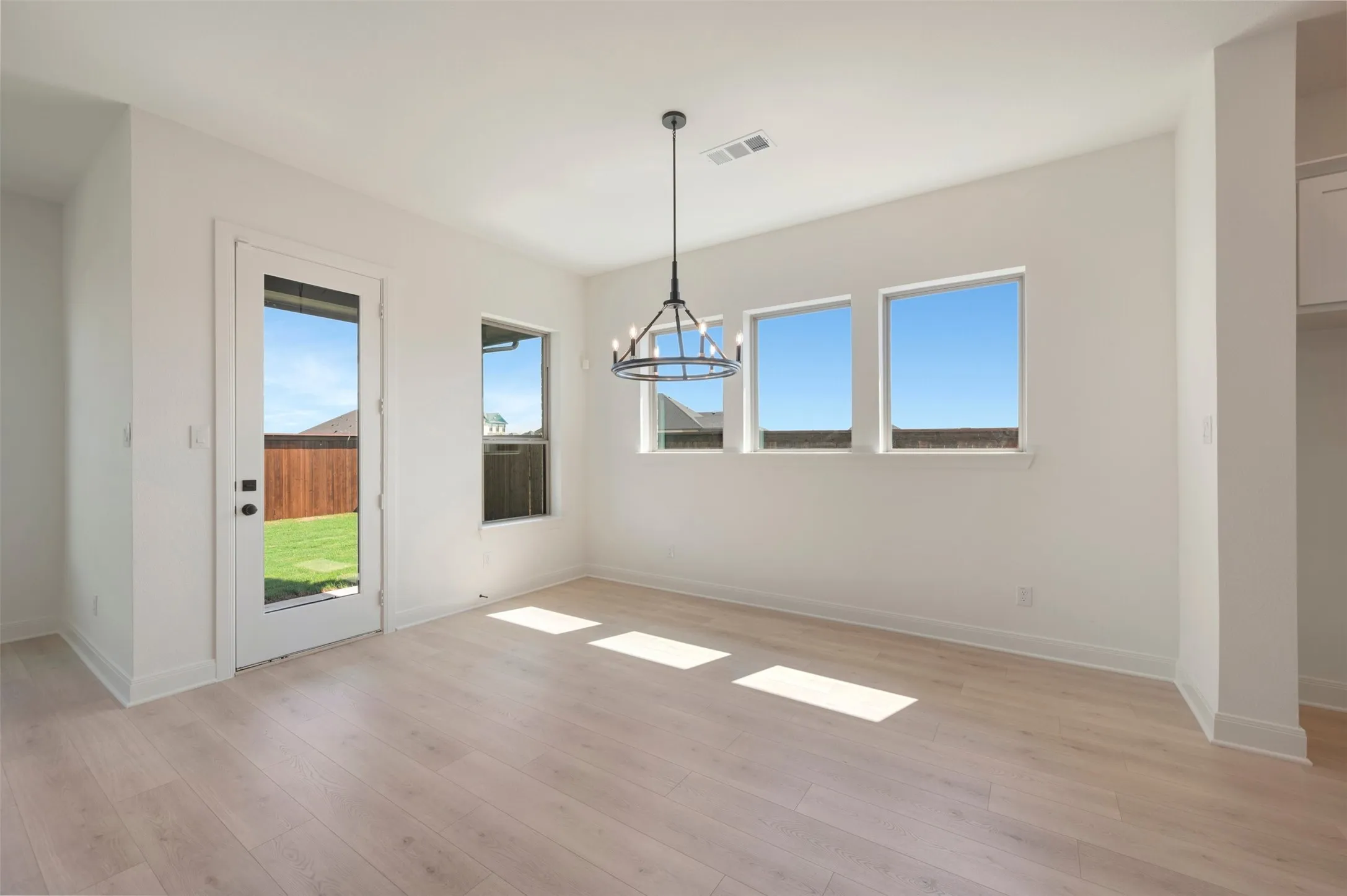 Wood-finish flooring, multiple windows, a glass-paneled door, and a wagon wheel chandelier