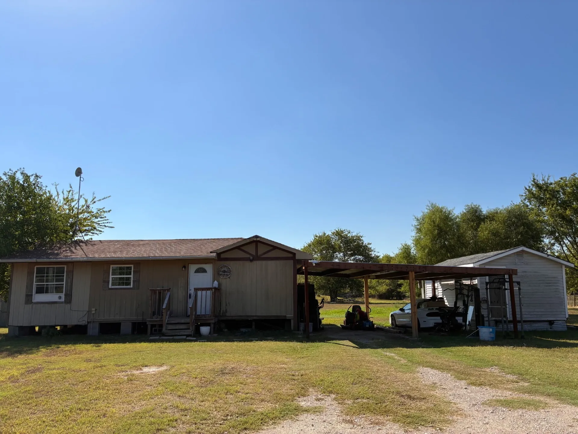 Single-story residence with a covered front porch entry, an attached carport, and a detached outbuilding