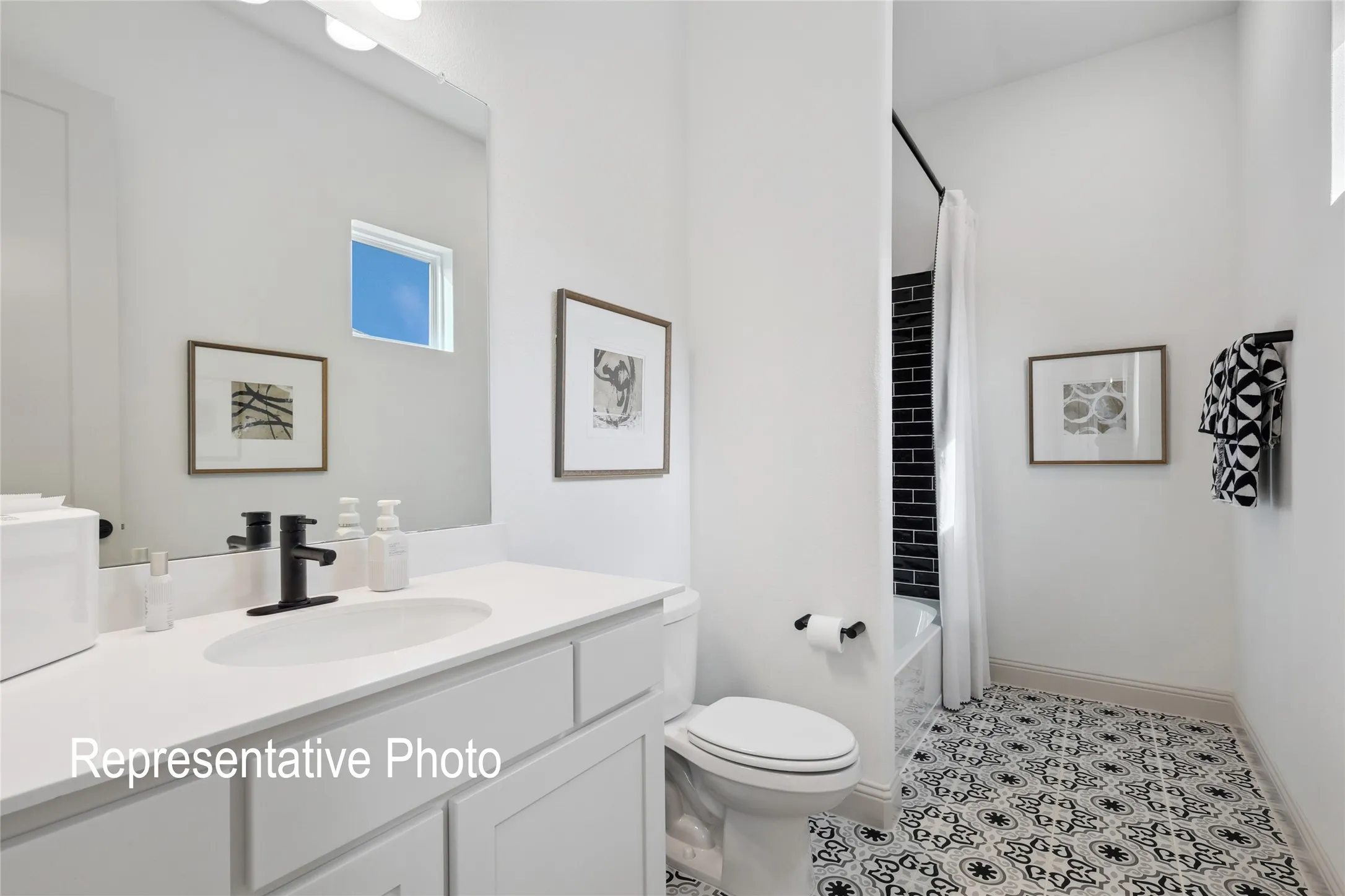 Bathroom featuring a white vanity with an undermount sink and matte black faucet, a built-in tub with black subway tile surround, patterned floor tiles, and a privacy window
