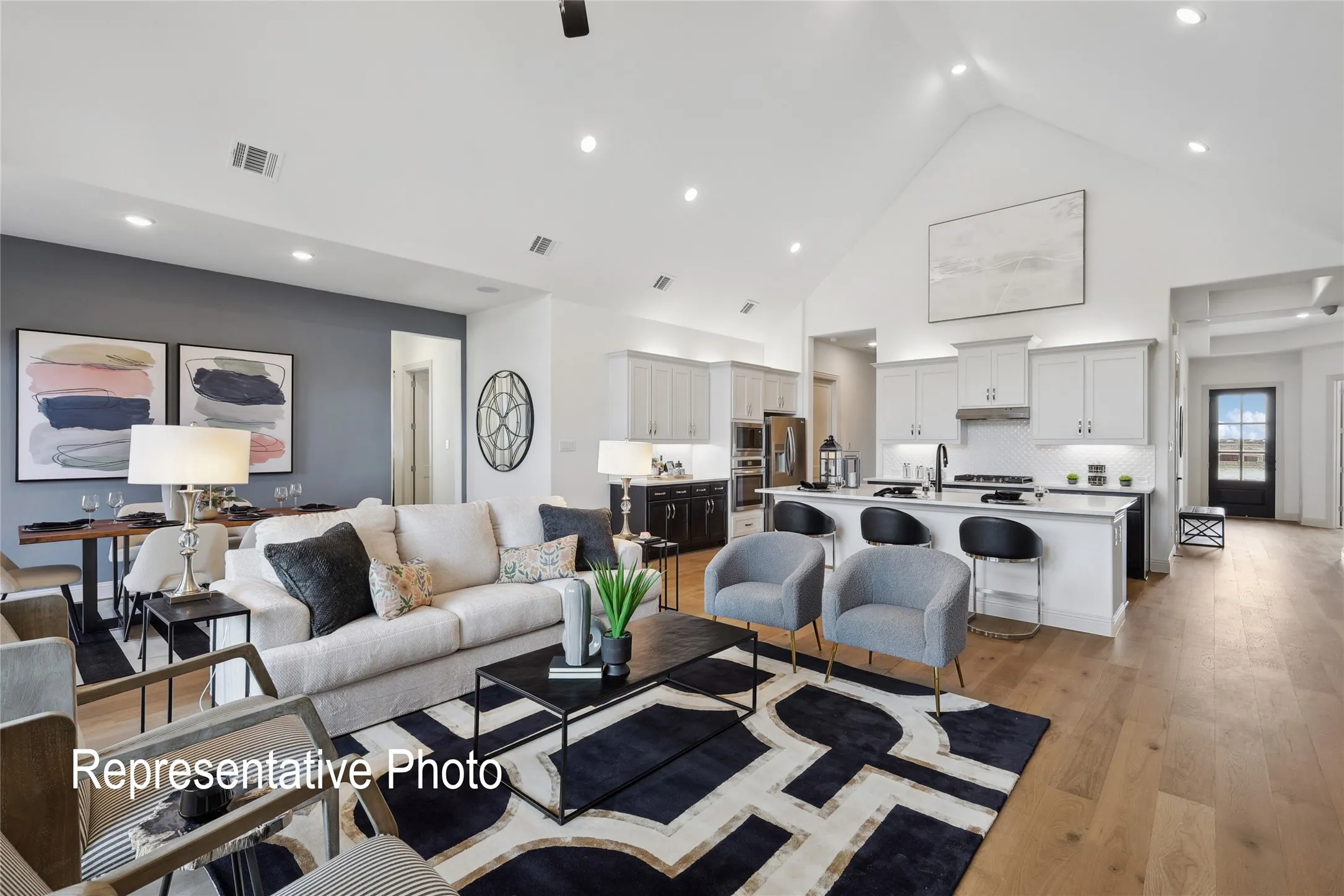 Open-concept living space featuring wood-finish flooring, a vaulted ceiling, recessed lighting, and a kitchen island with seating