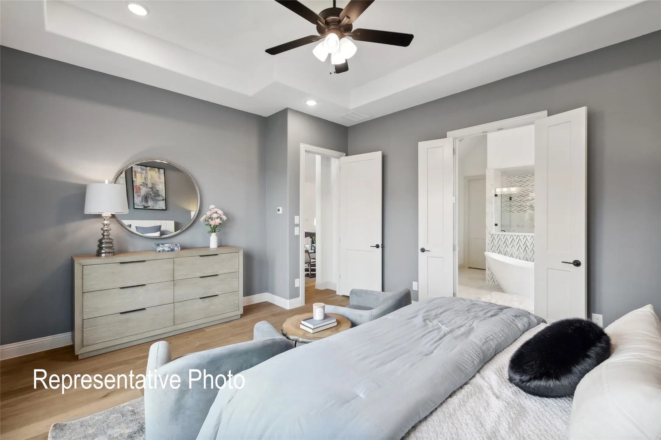 Bedroom featuring tray ceiling with recessed lighting, wood-finish flooring, and direct access to a full bathroom