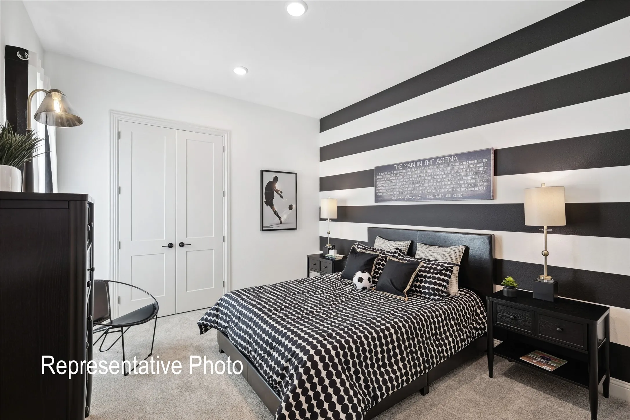 Bedroom featuring a black and white striped accent wall, light-colored carpet, recessed ceiling lighting, and white paneled doors with black hardware