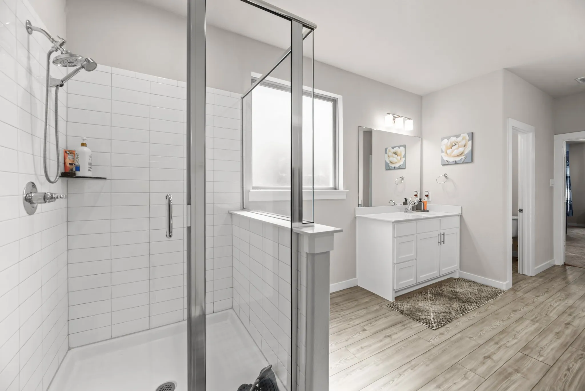 Spacious bathroom with a walk-in shower featuring white subway tile surround and a glass enclosure