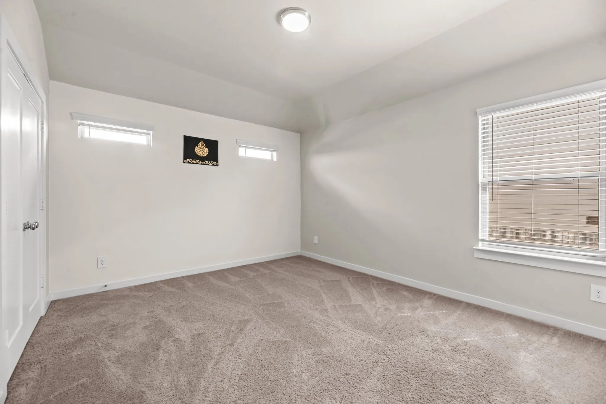 Carpeted interior space featuring neutral wall tones, a tray ceiling, and a flush-mount ceiling light