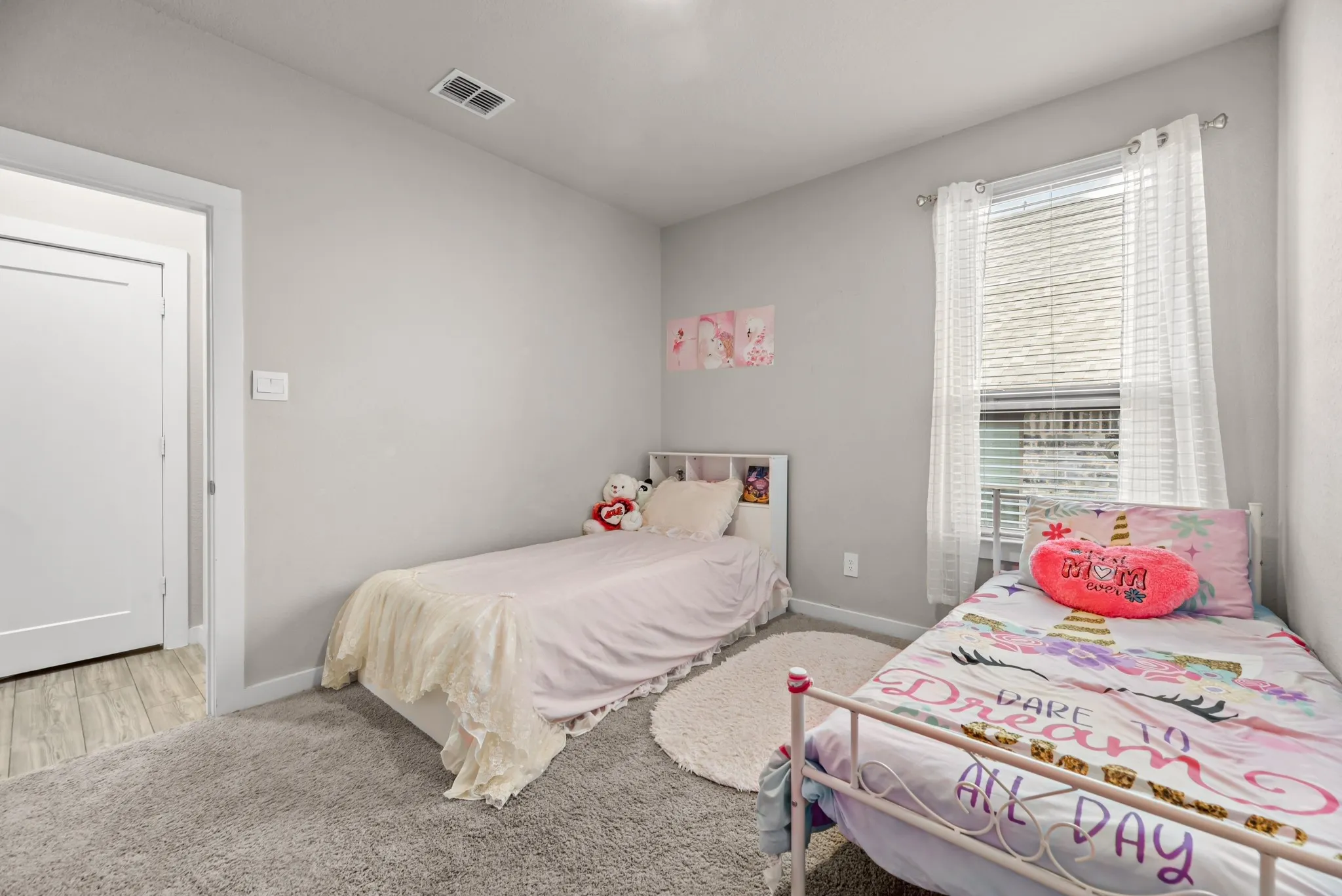 Bedroom featuring light gray wall paint, gray carpeting, a window with blinds and sheer curtains, and a white interior door with a two-panel design