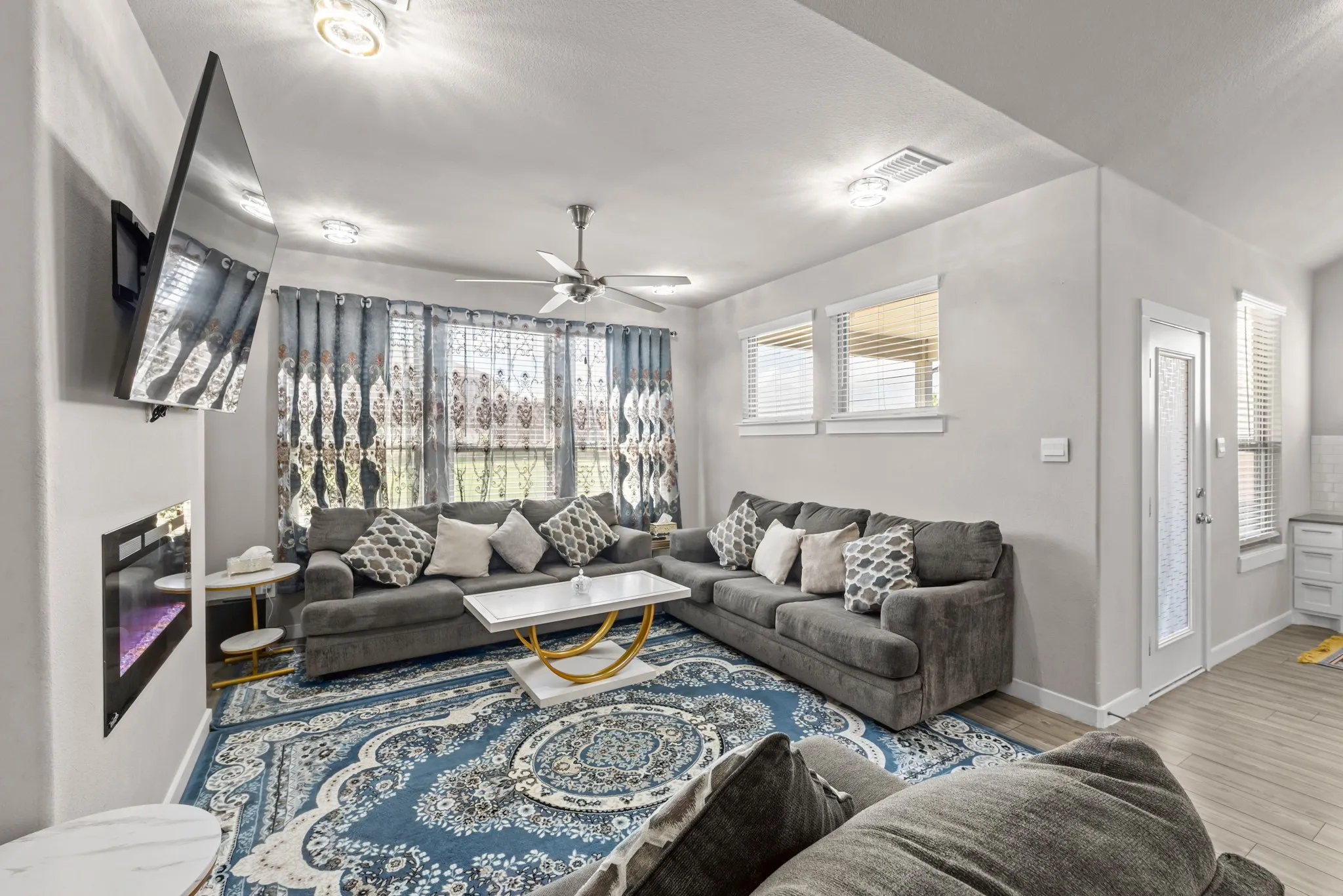 Open-concept living area with light gray walls, an integrated electric fireplace, and light wood-finish flooring