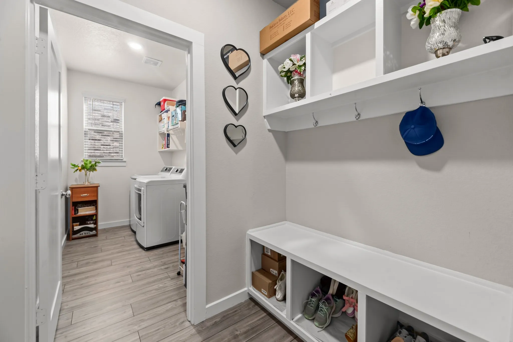 Built-in white storage bench with cubbies, upper shelving, and wall hooks
