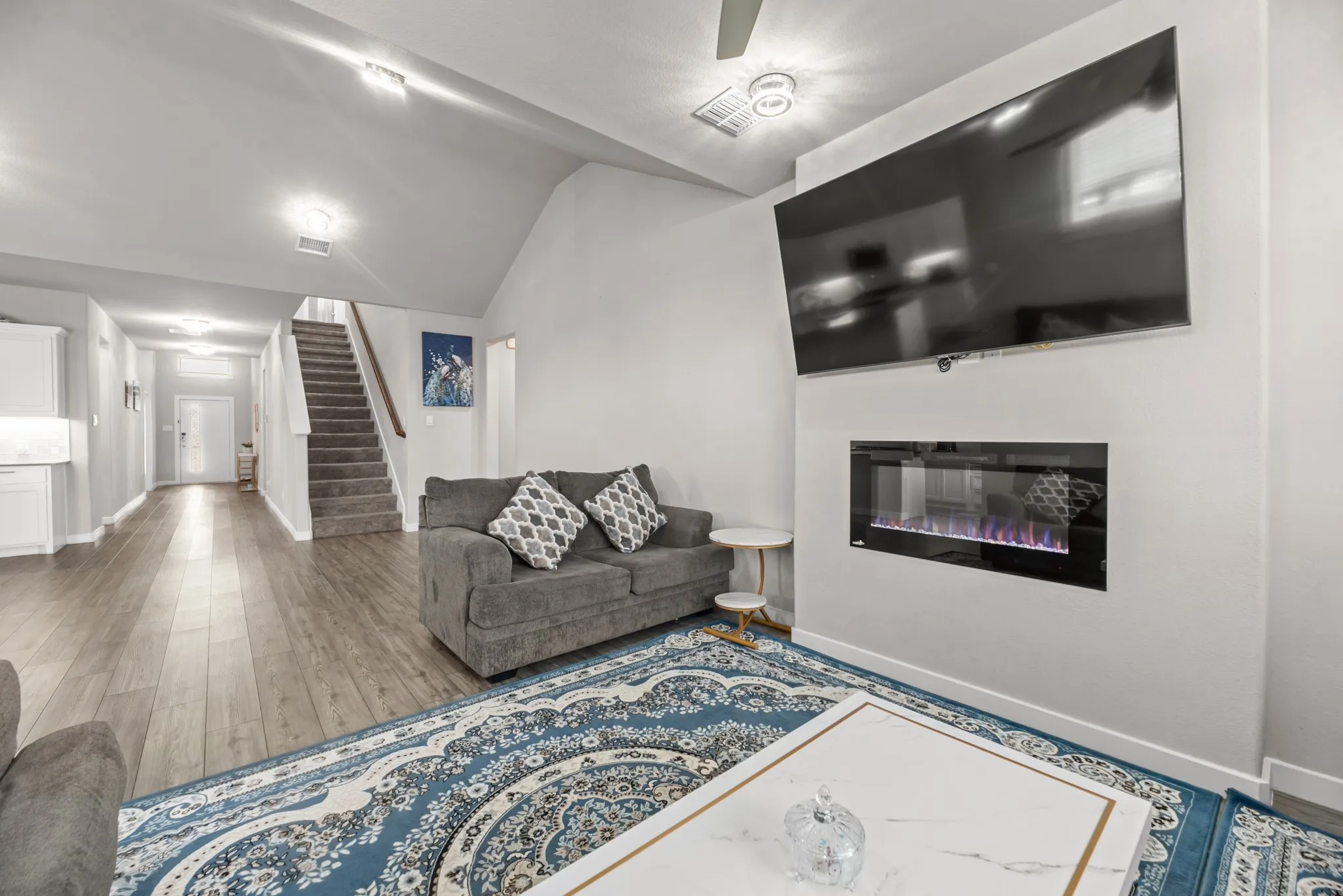 Living area featuring wood-finish flooring, a wall-mounted electric fireplace, and recessed lighting