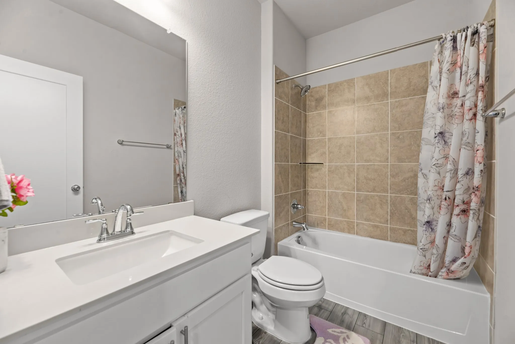 Bathroom featuring a white vanity with an integrated sink, polished chrome faucet, and expansive wall mirror