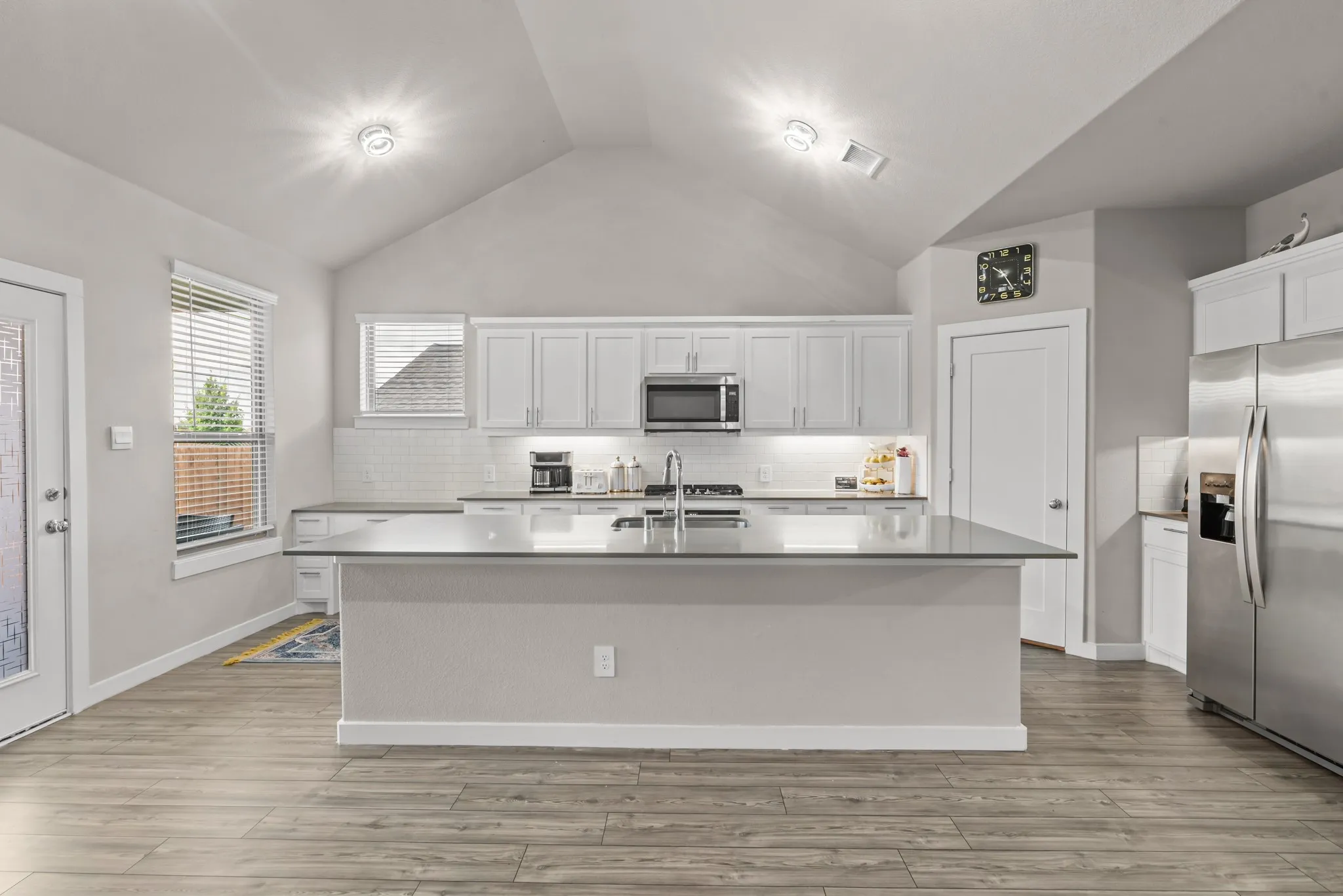 Bright kitchen featuring a vaulted ceiling and wood-finish flooring