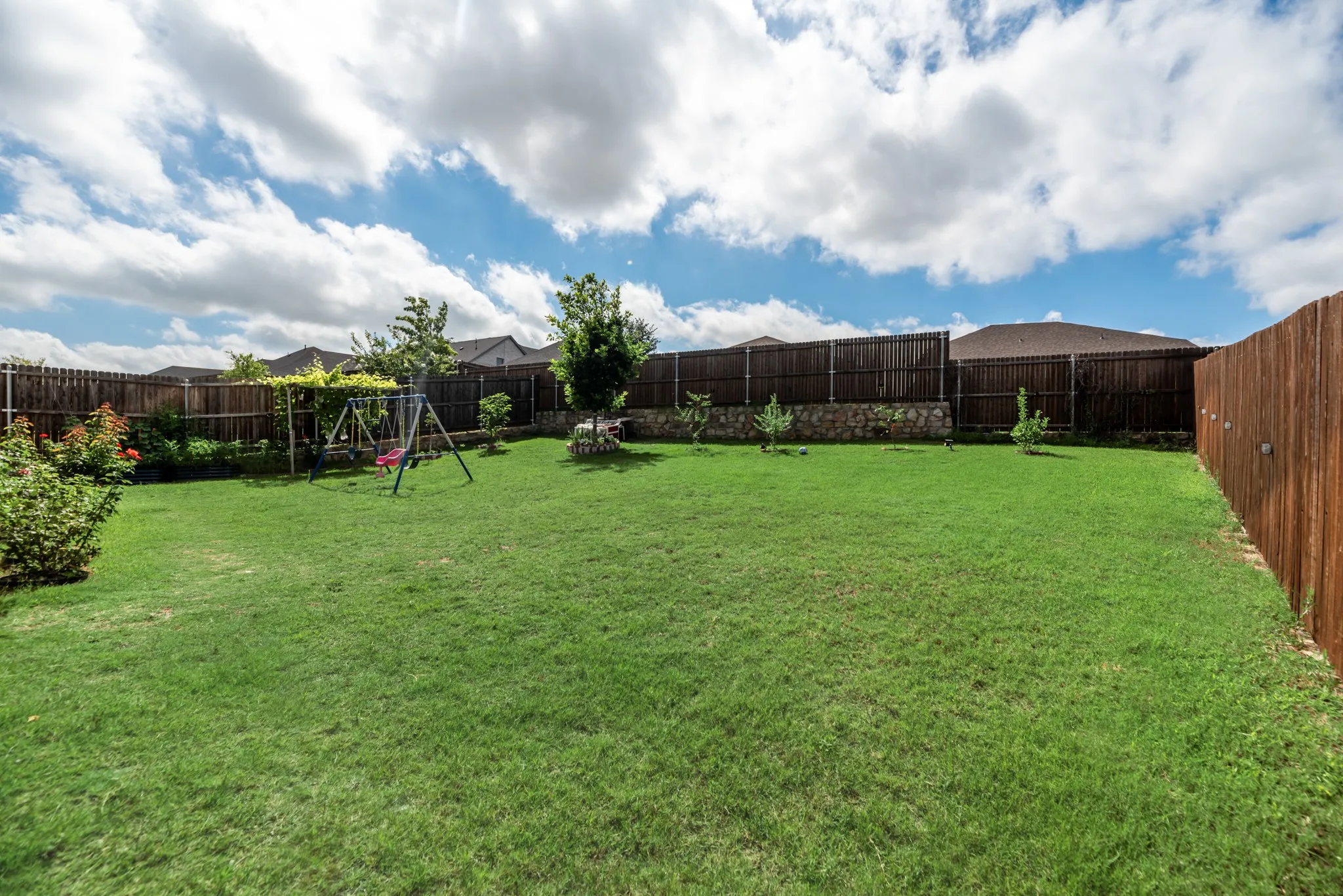 Expansive lawn area with a full wood privacy fence and mature trees