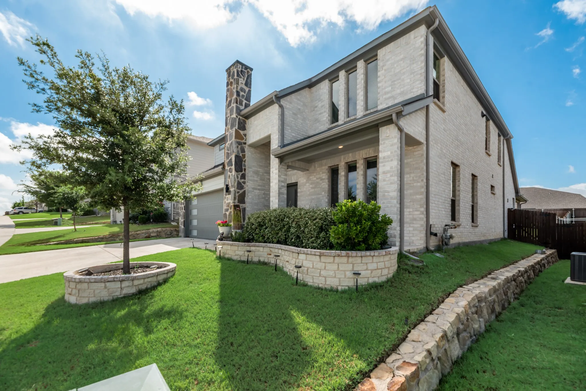 Contemporary two-story residence featuring light brick masonry and a stone chimney accent