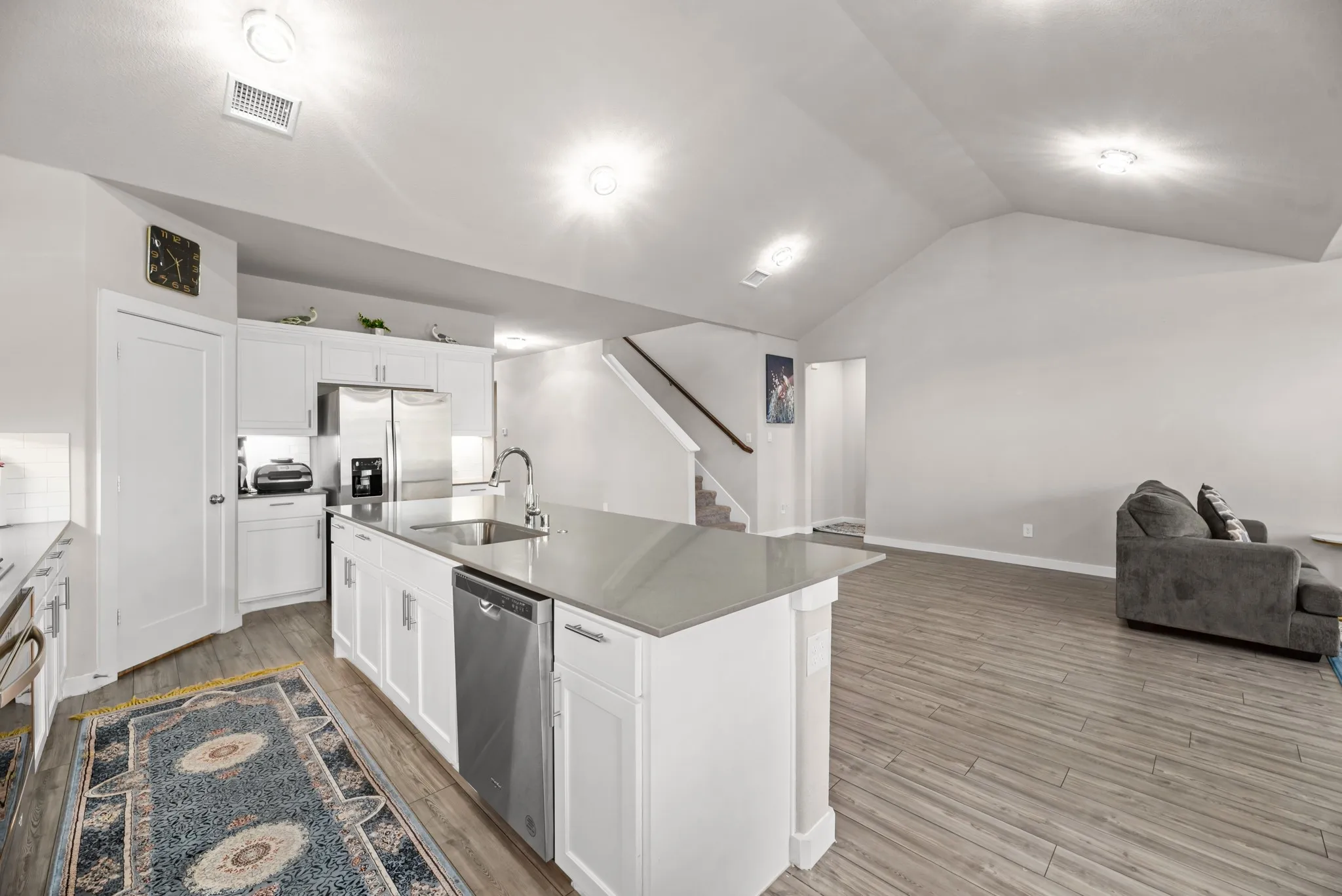 Modern kitchen island with an undermount sink, stainless steel dishwasher, and light-toned countertop