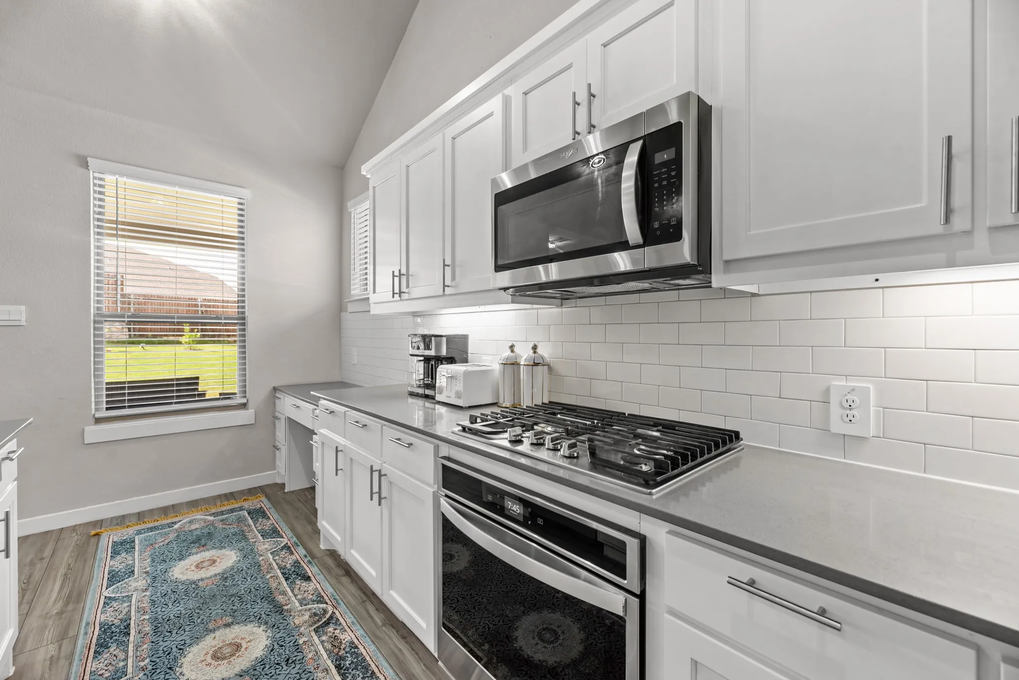 Bright kitchen featuring white shaker cabinetry, stainless steel appliances, a gas range with oven, subway tile backsplash, and light-tone countertops
