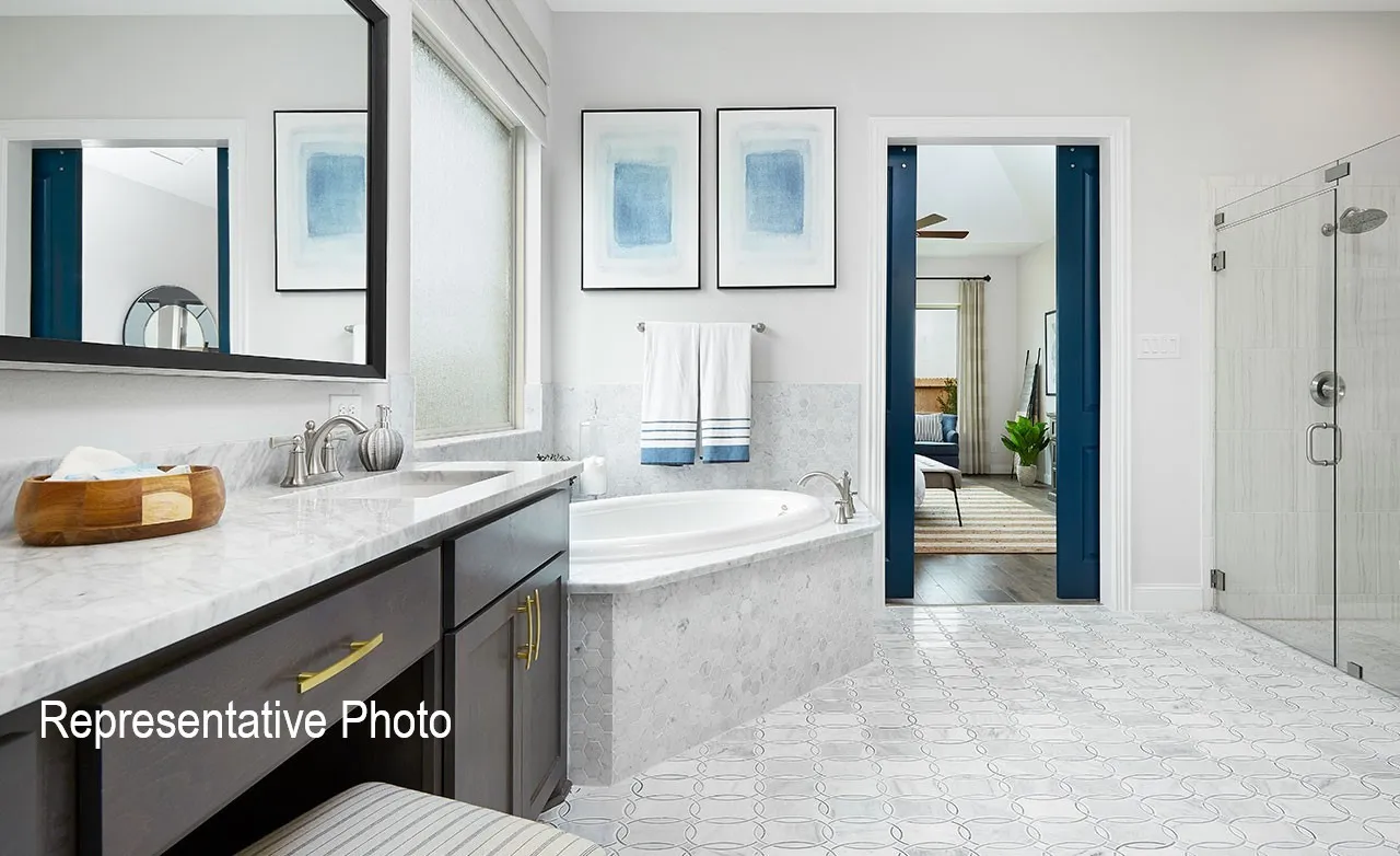 Bathroom featuring a dual vanity with a light-toned countertop, an integrated soaking tub, a glass-enclosed shower, and decorative floor tiling