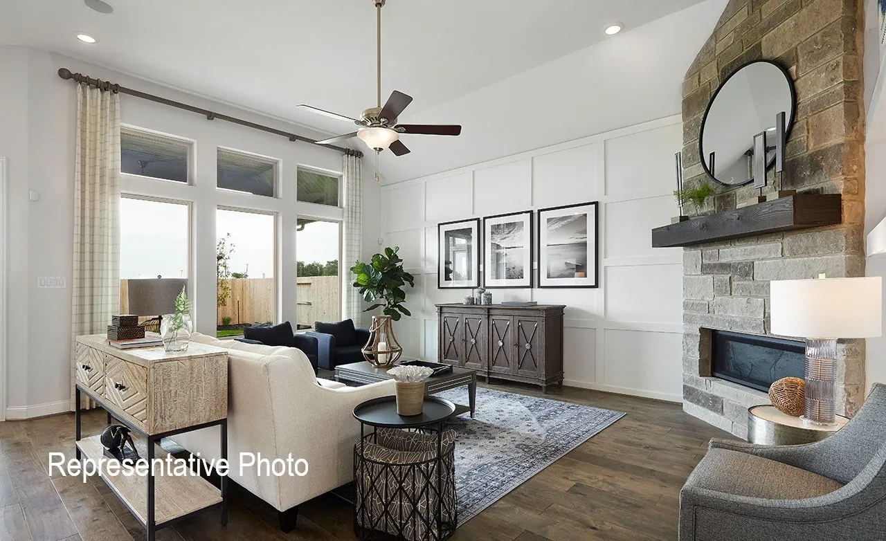 Living room featuring wood-finish flooring, a stone-clad fireplace with a dark wood mantel, and large transom windows