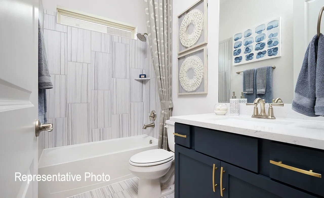 Modern bathroom featuring a deep blue vanity with gold-tone hardware, a white countertop, and an undermount sink