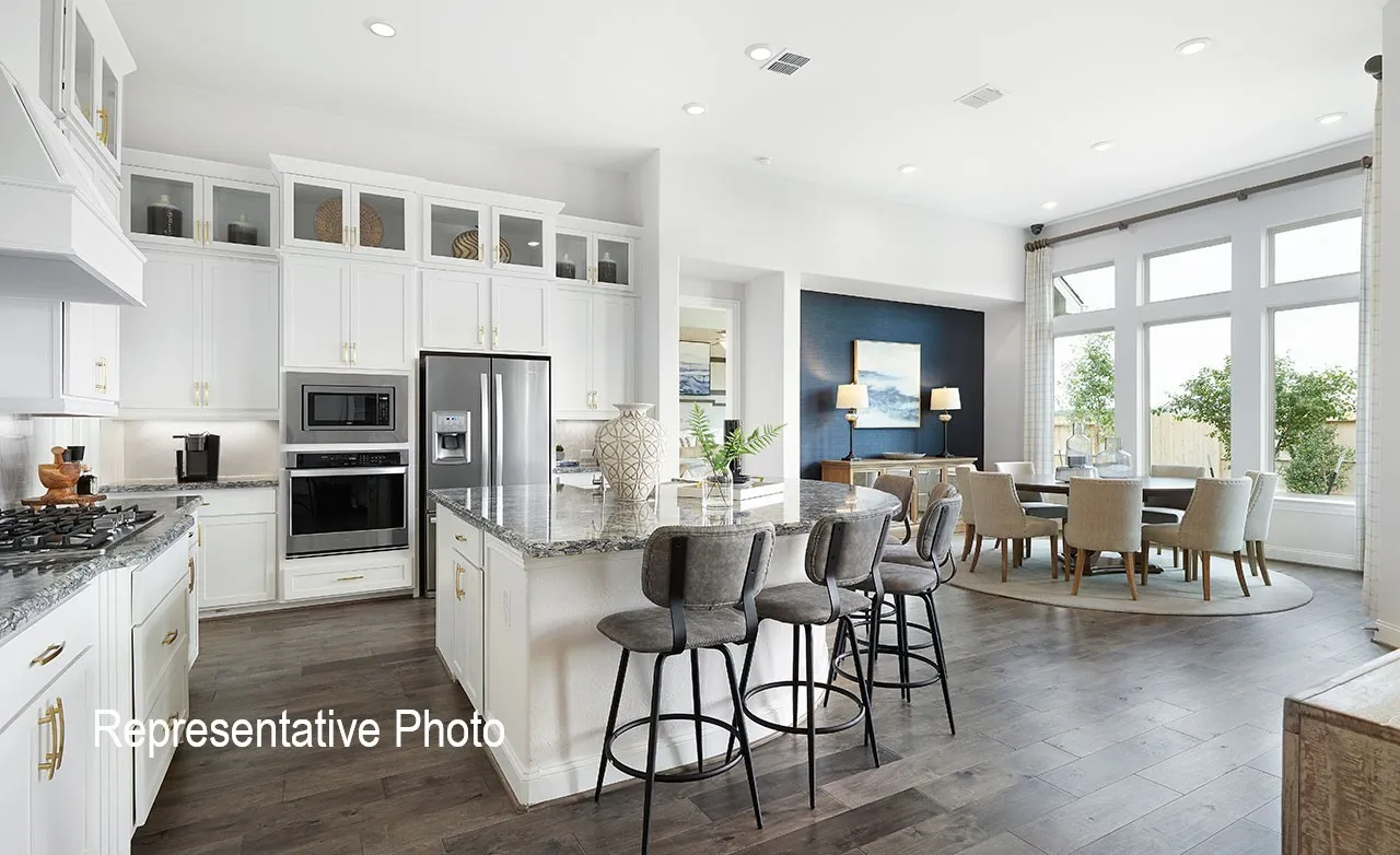 Open-concept kitchen and dining area featuring a spacious island with counter seating, stainless steel appliances, white cabinetry, and wood-finish flooring