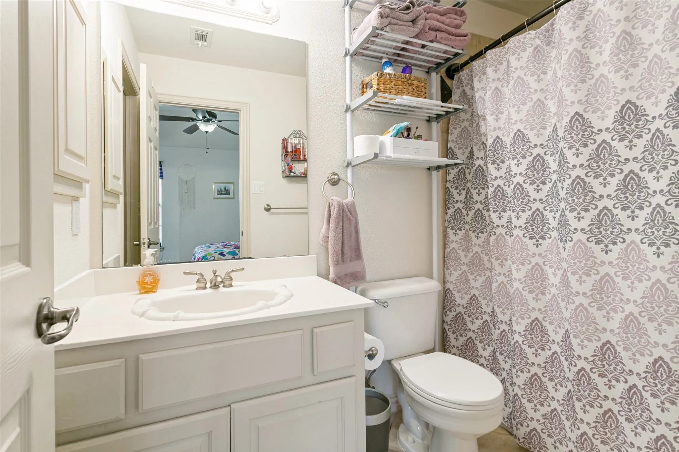 Bathroom featuring a white vanity with an integrated sink, brushed nickel faucet, and a large wall mirror