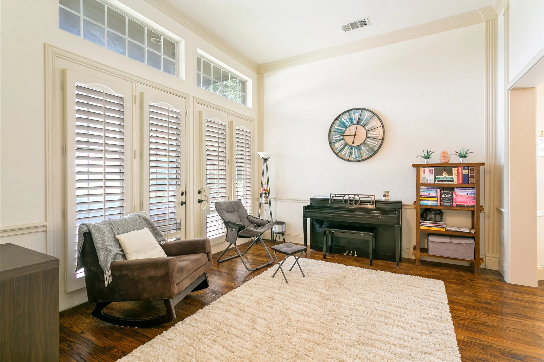 Living area featuring tall French doors with integrated plantation shutters and transom windows