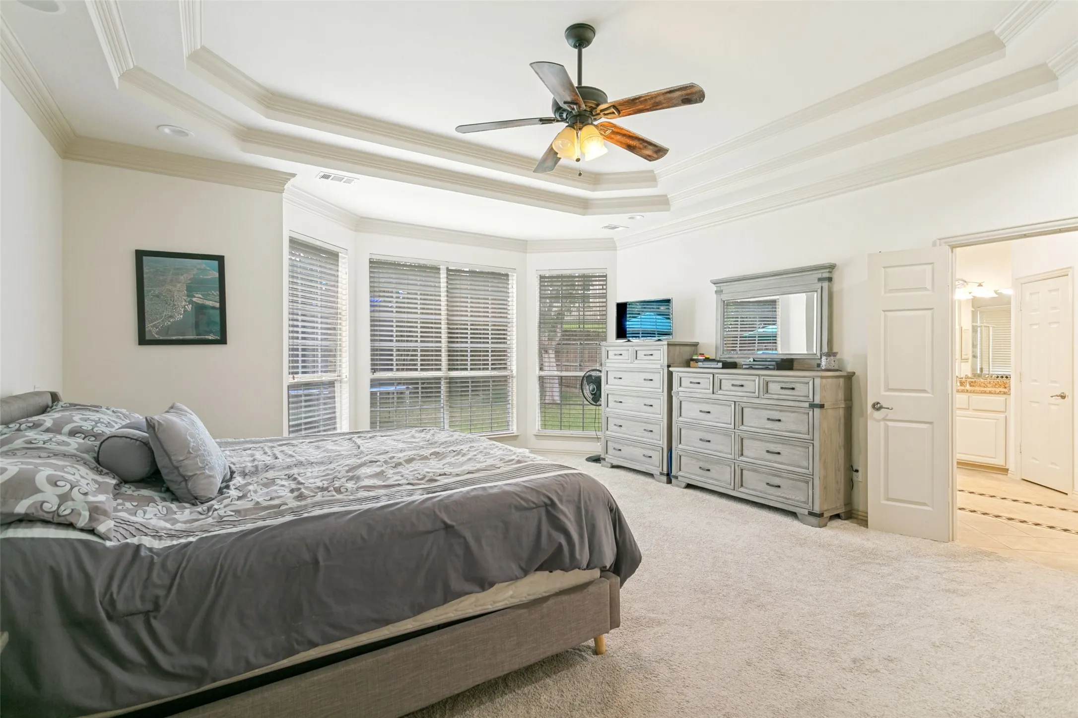 Spacious room featuring a tray ceiling with crown molding, a ceiling fan, and carpeted flooring