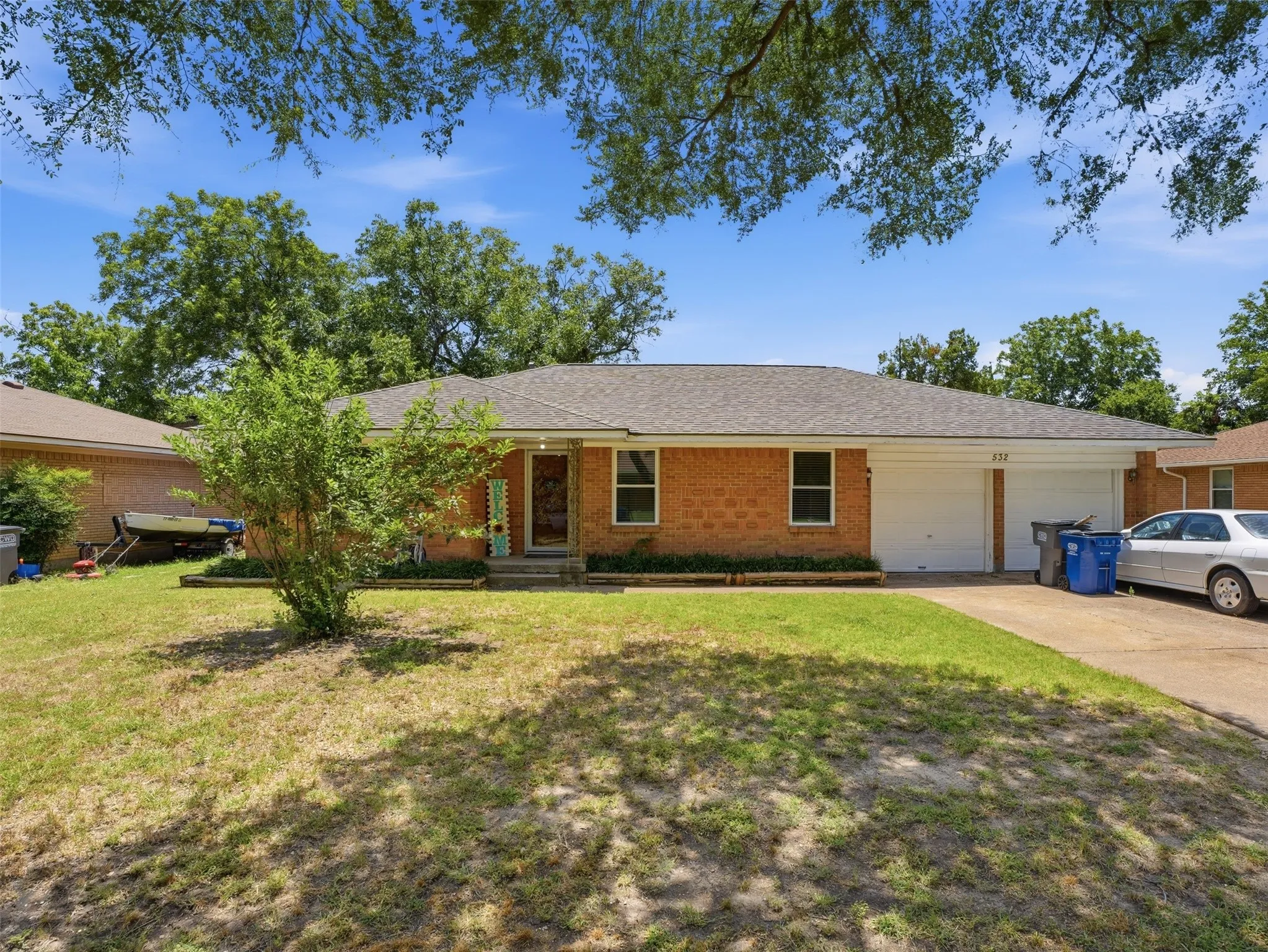 Brick exterior residence featuring a two-car garage, covered porch entry, and a front yard