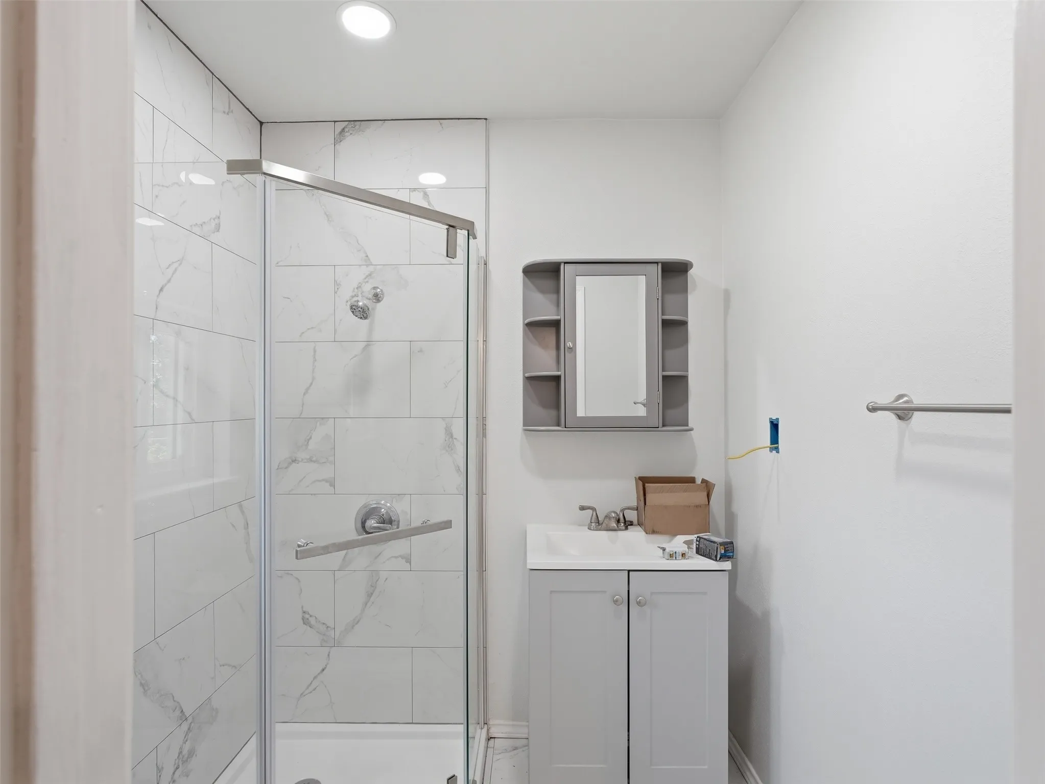 Shower with clear glass enclosure and white tile surround, featuring chrome fixtures