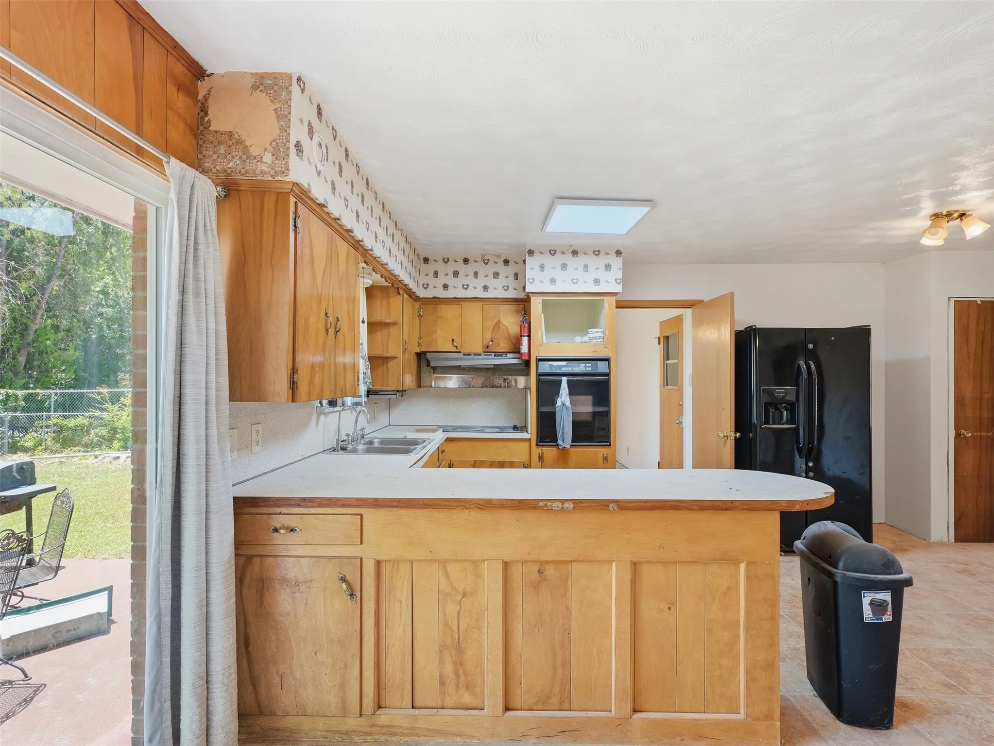 Kitchen featuring wood cabinetry, white countertops, a built-in oven, and a black refrigerator
