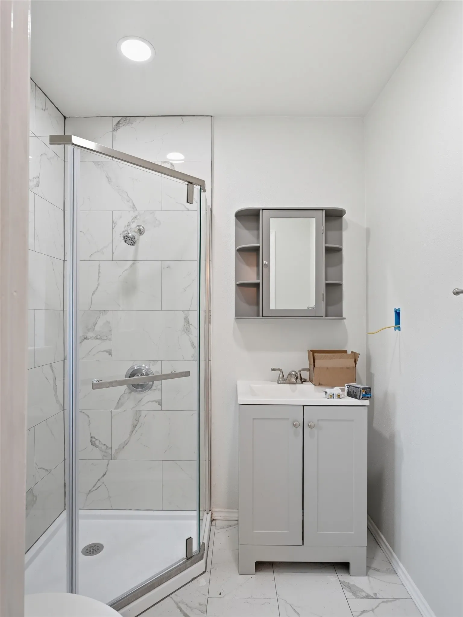 Shower with glass enclosure and white marble-look tile surround