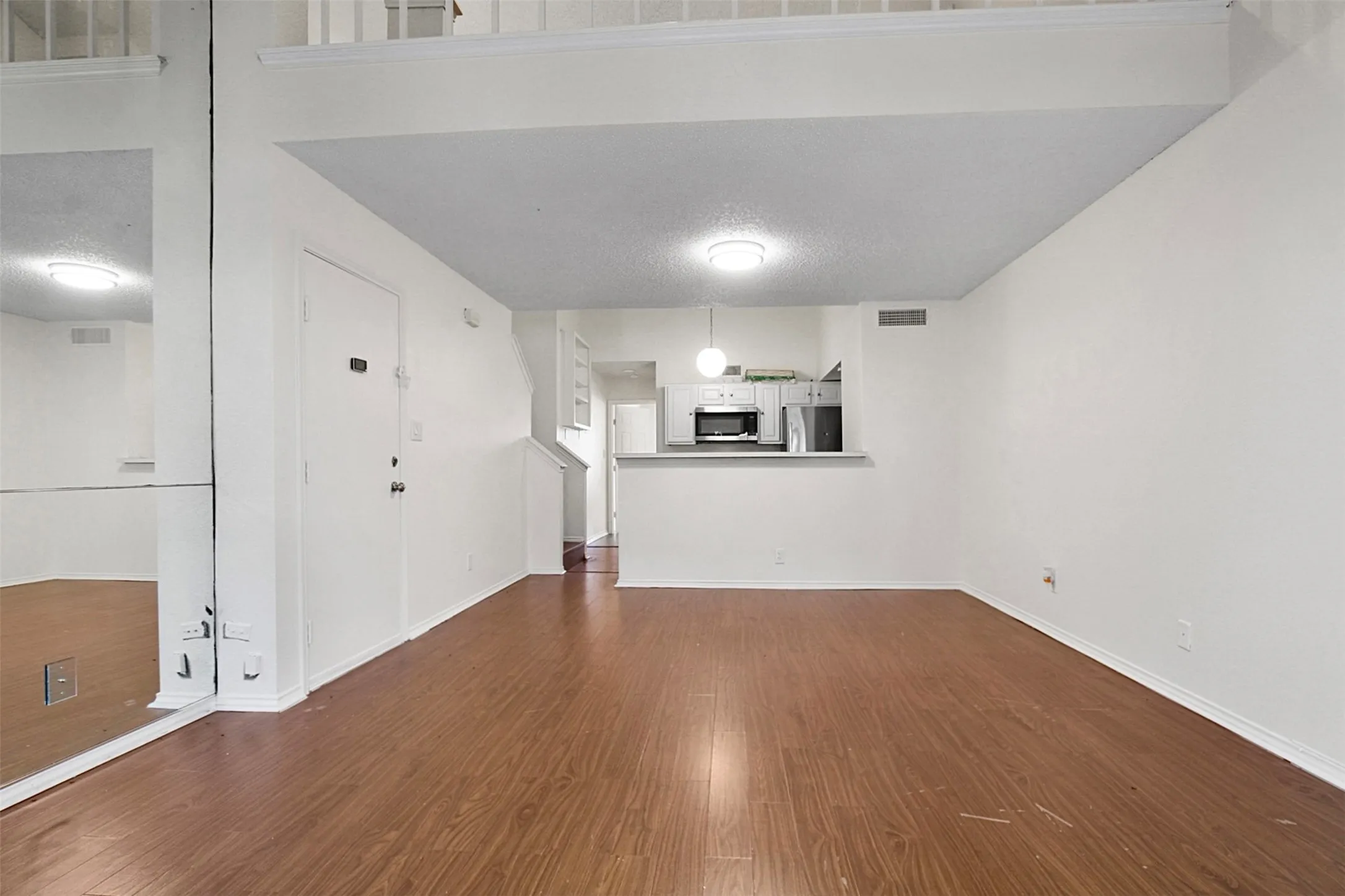Open-concept living space featuring wood-finish flooring, white walls, and a lofted ceiling