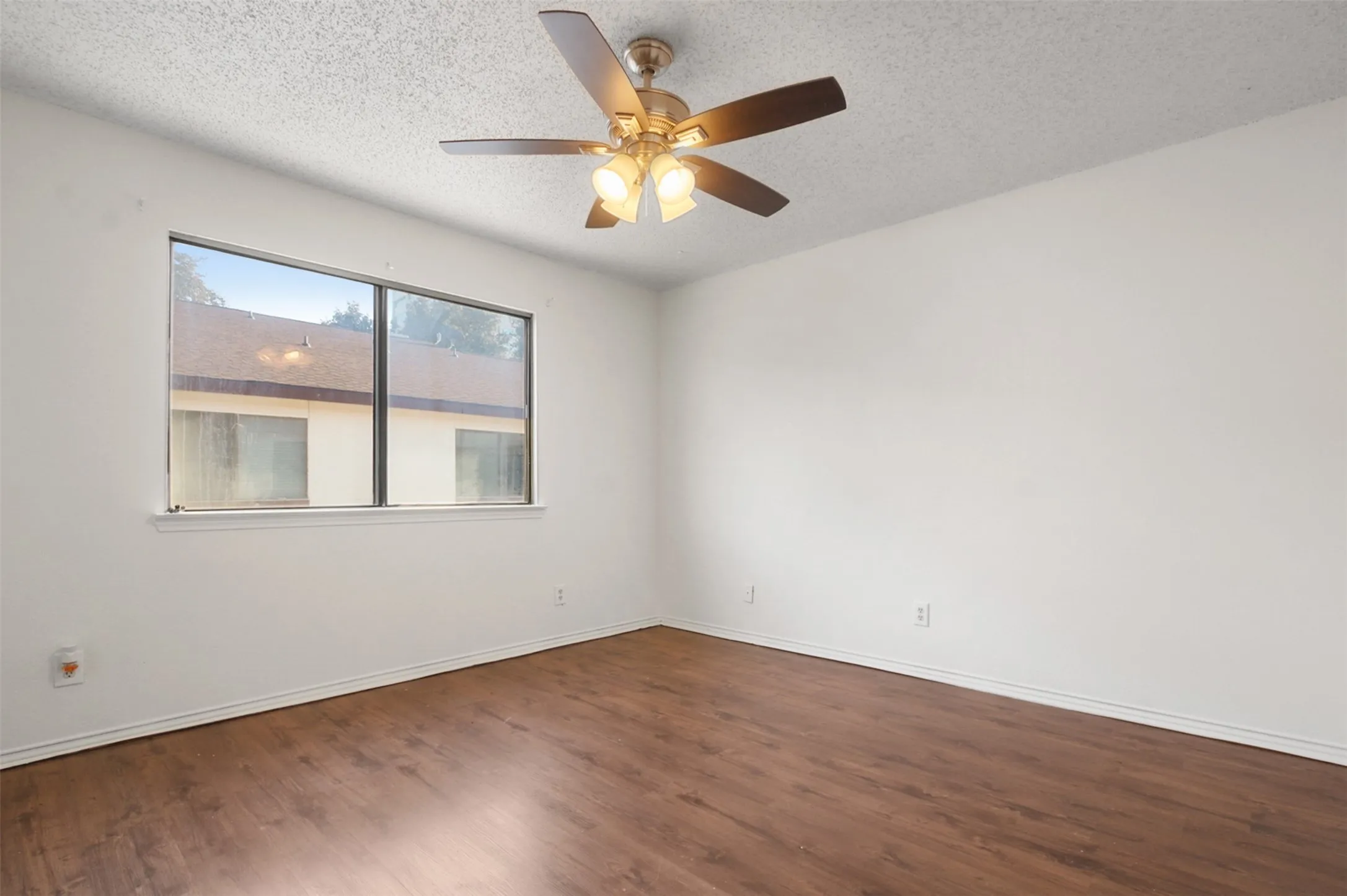 Bright interior space featuring wood-finish flooring, white baseboards, and a large window