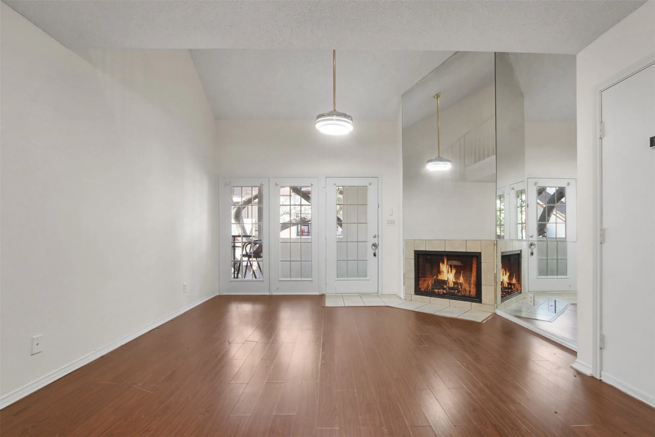 Living area featuring wood-finish flooring, a vaulted ceiling, and dual pendant lighting fixtures