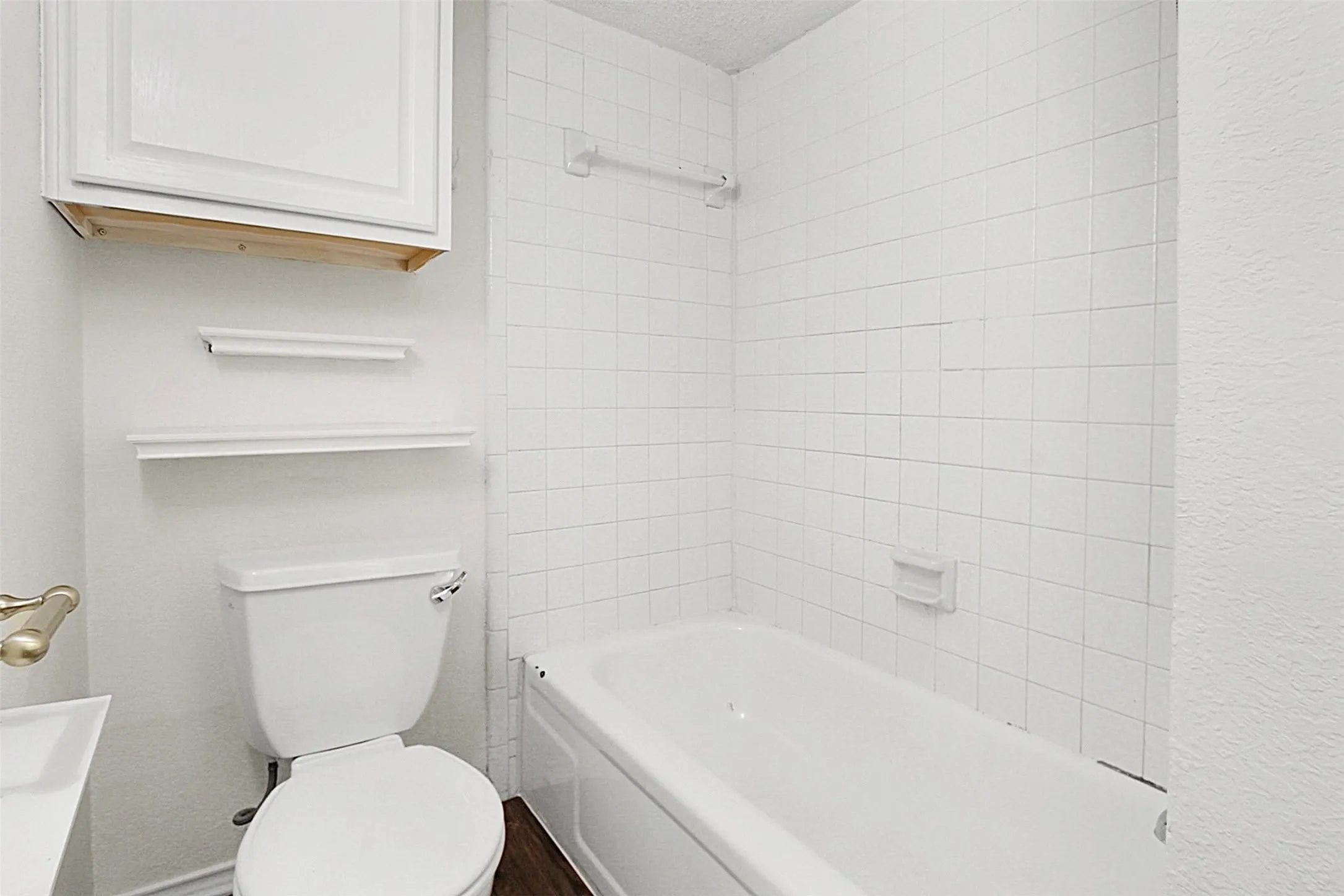 Bathroom featuring a white porcelain bathtub, white square wall tiling, and a white toilet