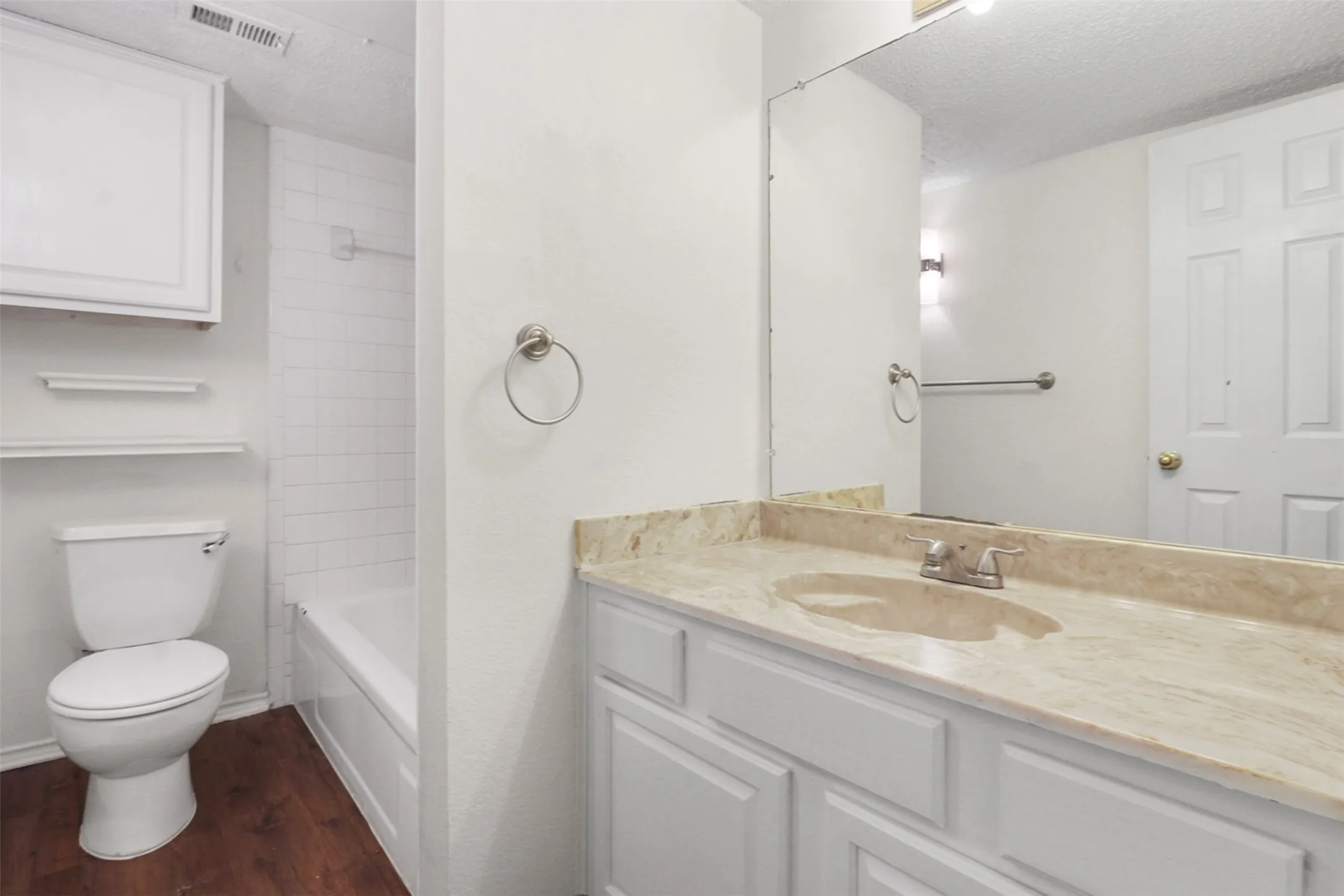 Bathroom featuring a single vanity with an integrated sink, a light-toned stone countertop, and white cabinetry