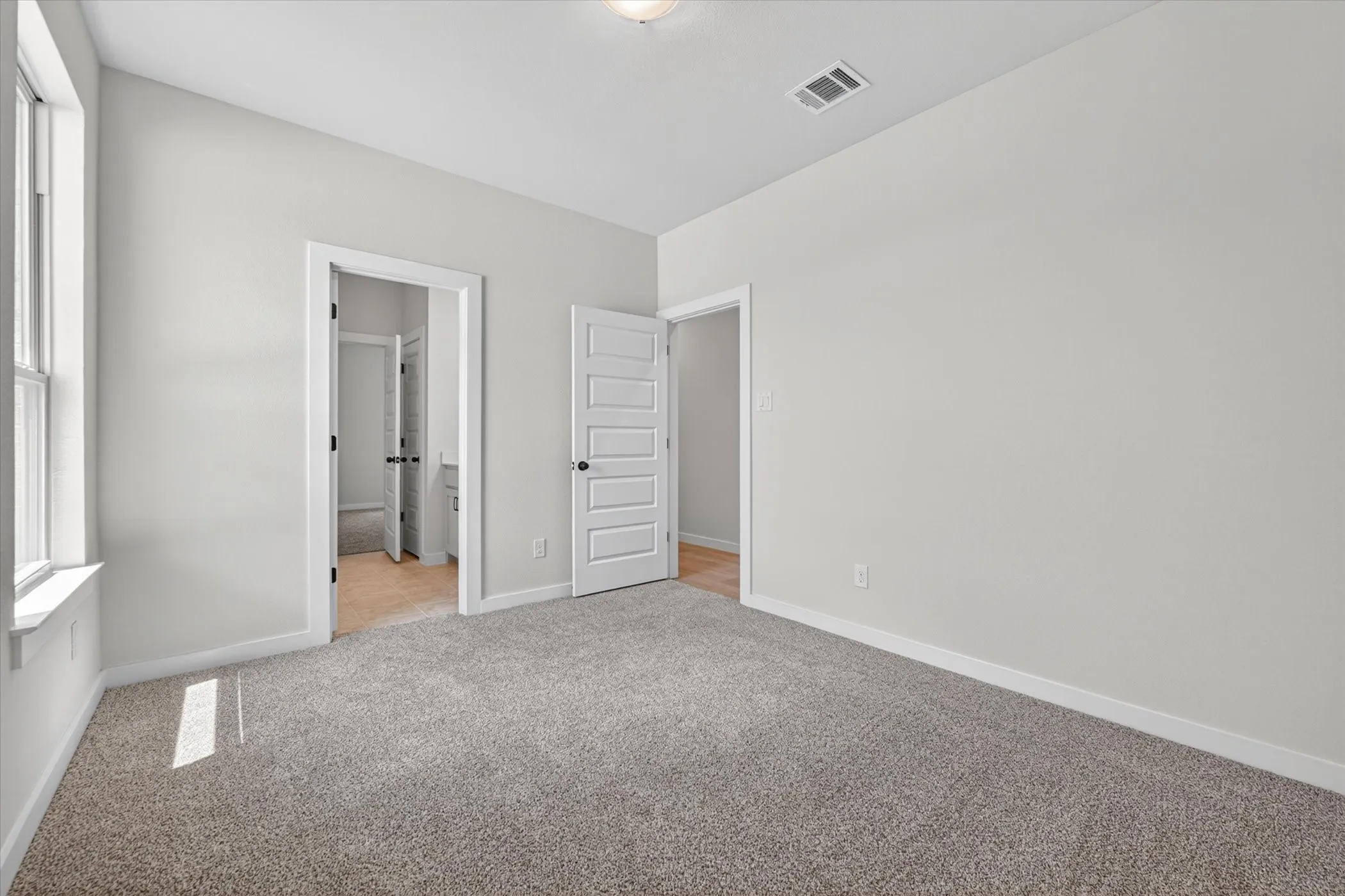 Spacious room with light gray wall paint, gray carpet, white trim, and a window with a white frame